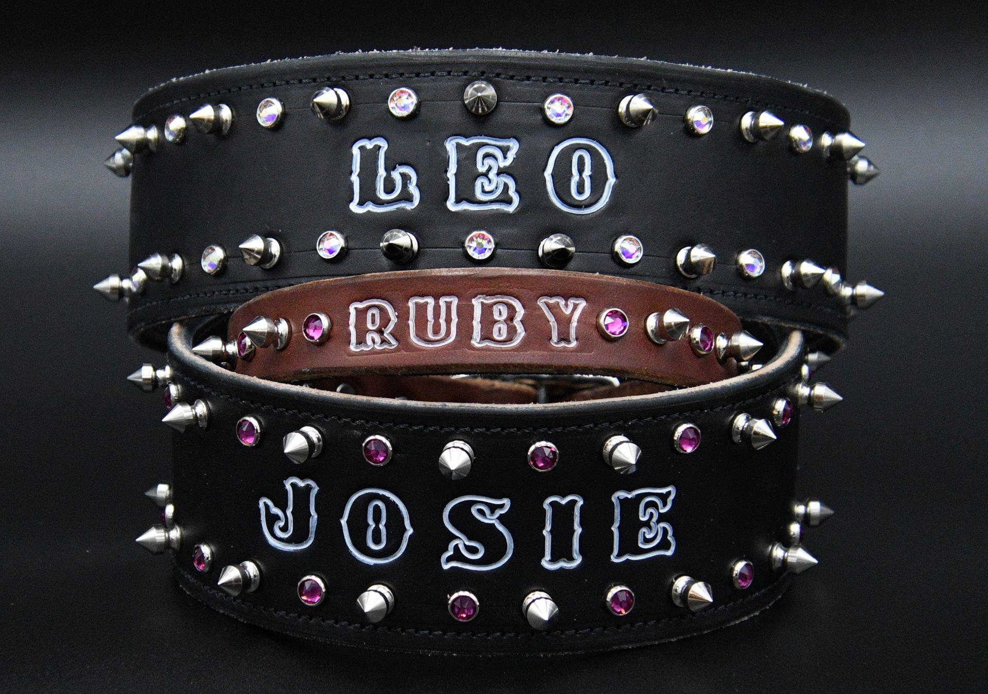 Tan leather studded wrist cuff with metal spikes on a dark green fabric background
