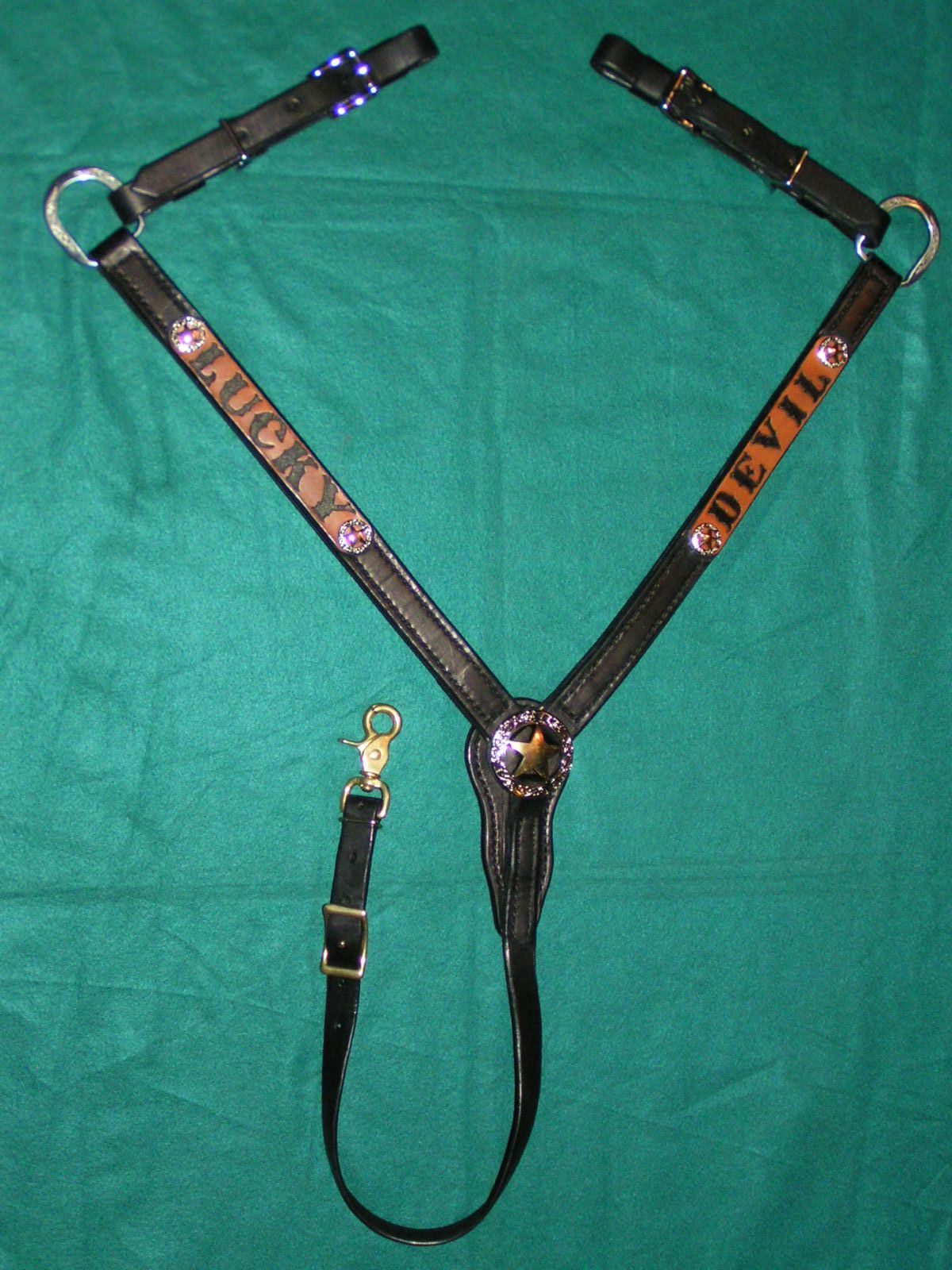 Tan western saddle with brown leather and black straps displayed on grass outdoors