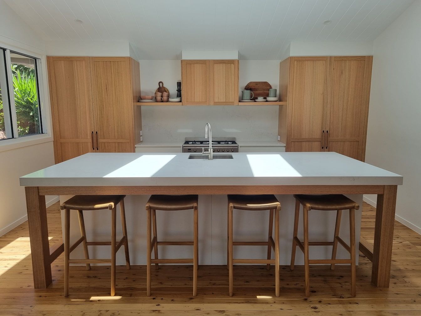 Modern kitchen with a large island, stools, wood cabinets, and white countertops