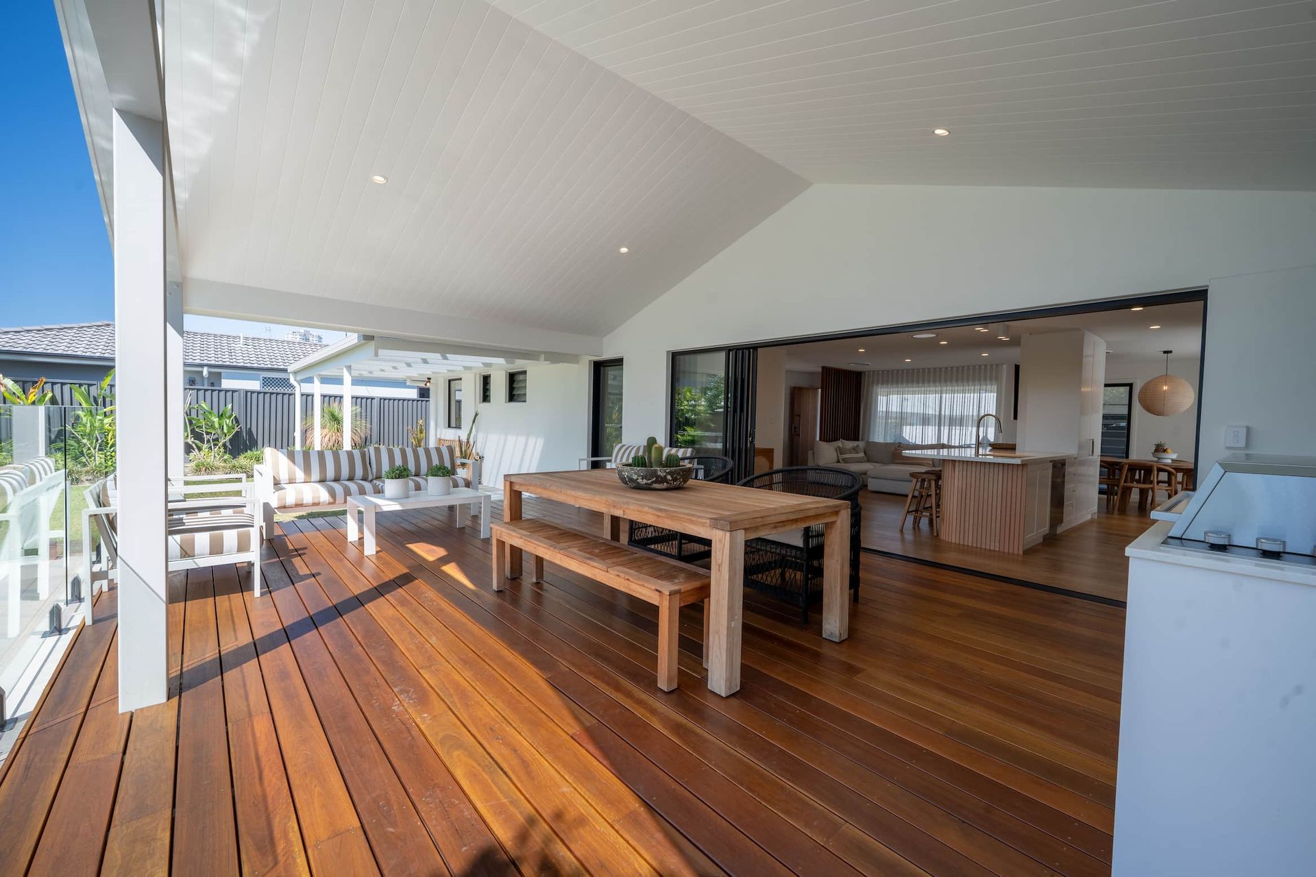 Wooden deck with a dining table and bench, leading to a home interior.