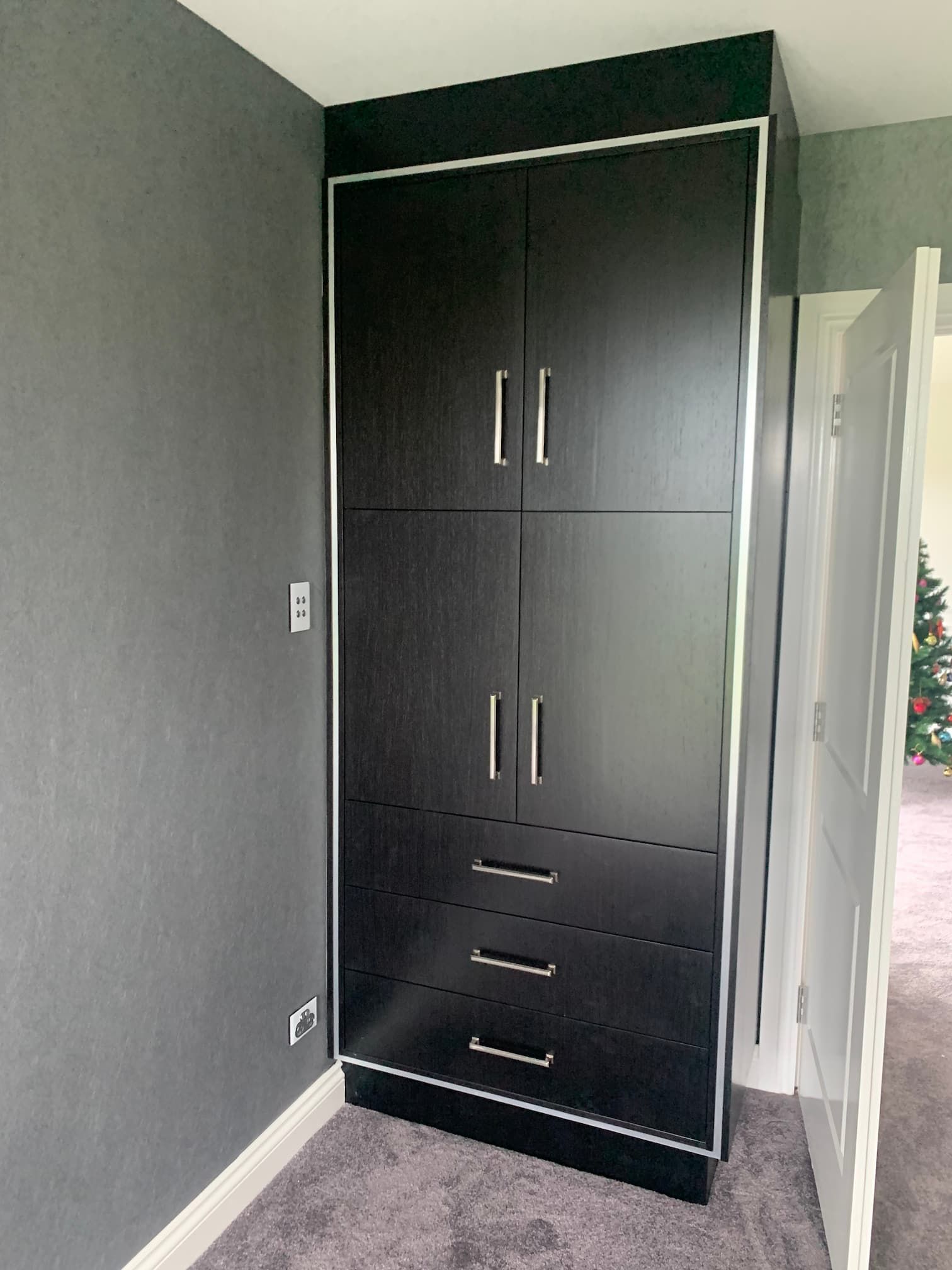 Black built-in wardrobe in a gray room with two doors and three drawers underneath