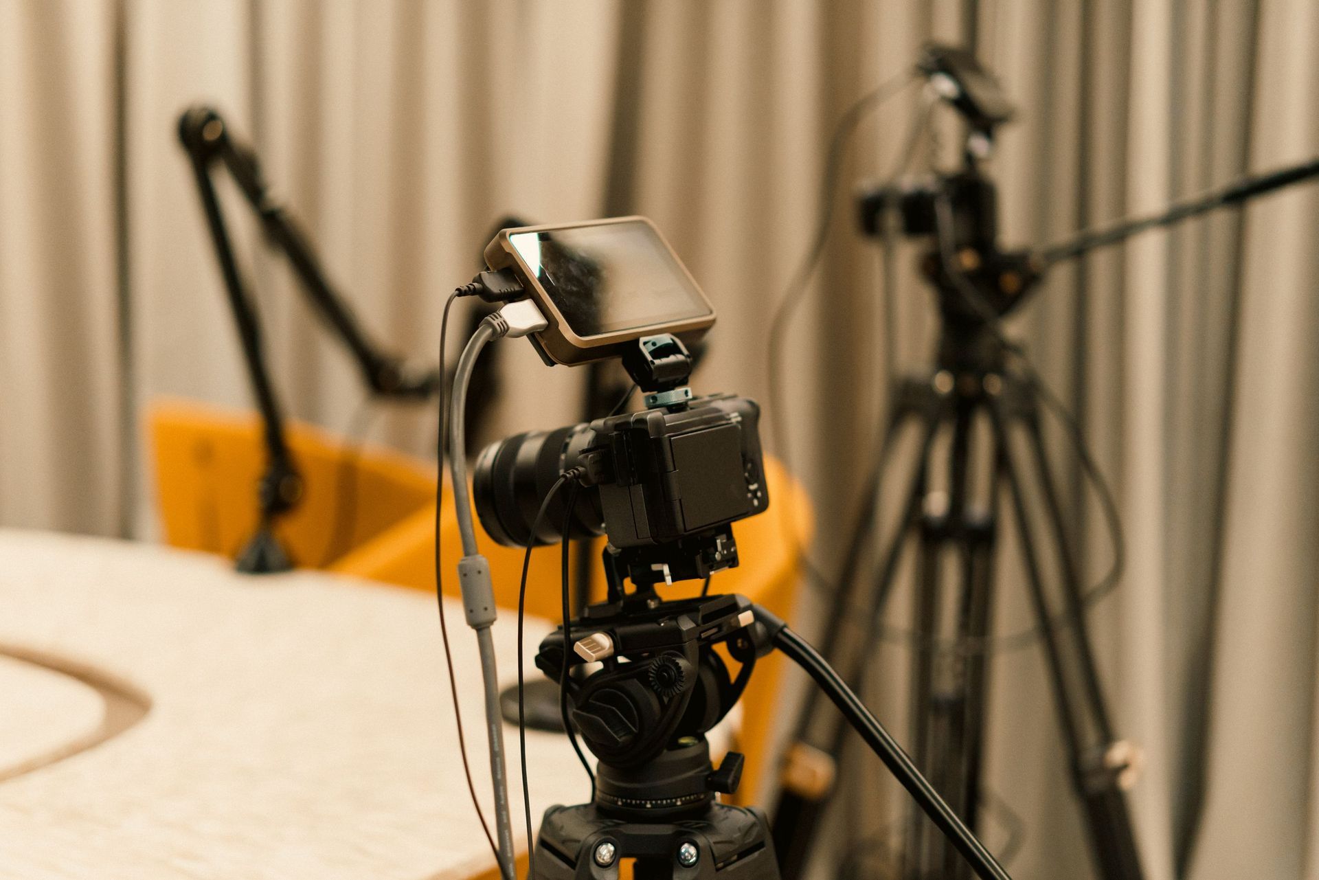 Camera on a tripod in a studio with microphones and blurred equipment in the background