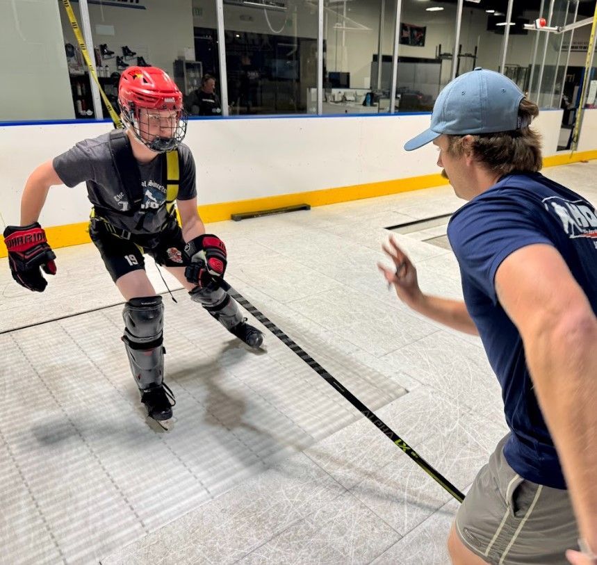 hockey player receiving instruction from coach on a skating treadmill
