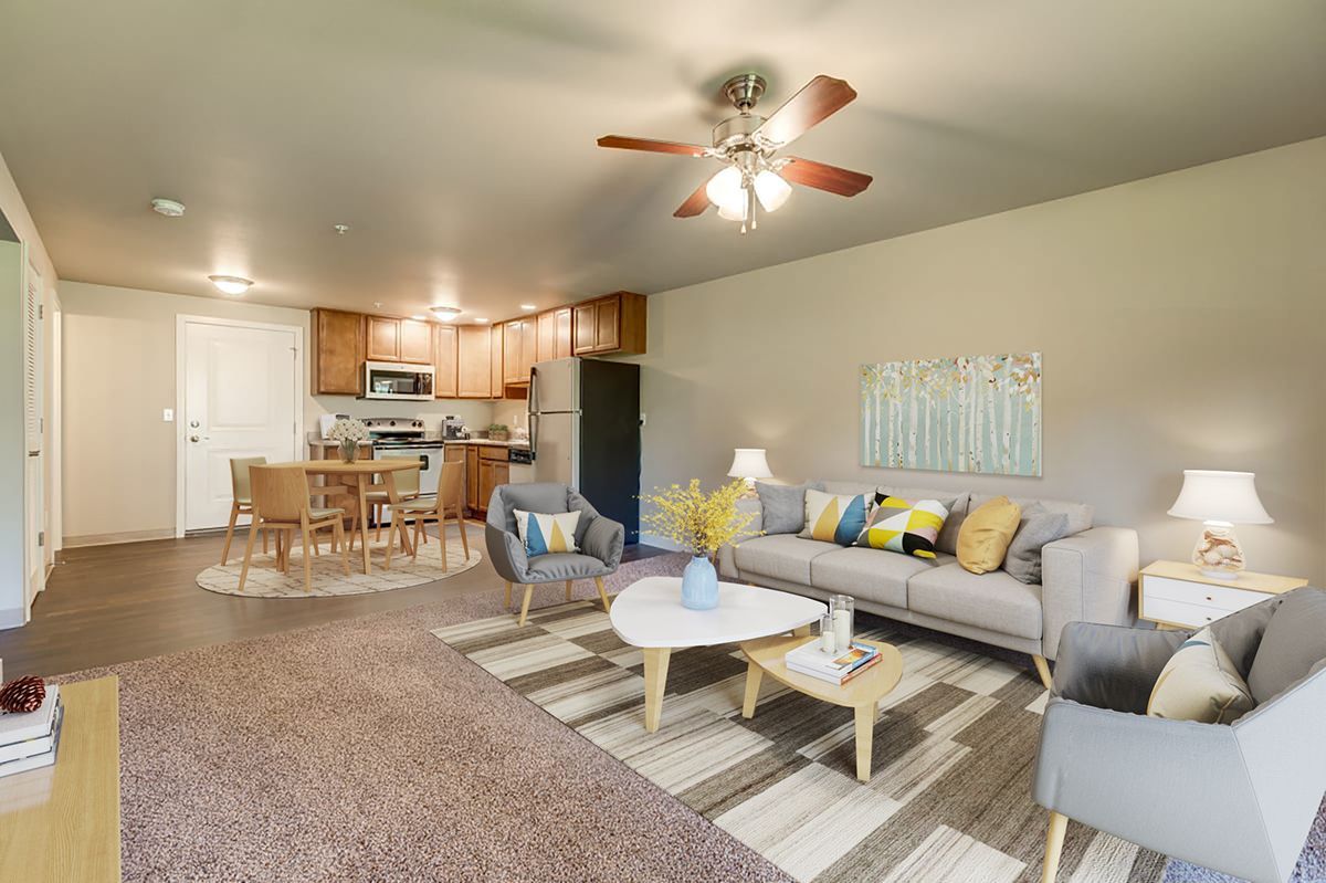 a living room with a couch , chairs , coffee table and ceiling fan .