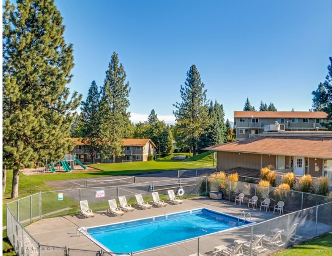 a large swimming pool is surrounded by chairs and a fence .