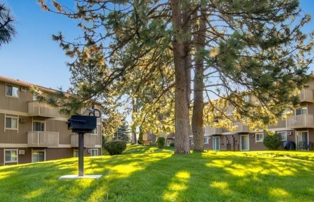 there is a mailbox in the middle of the grass in front of a building .