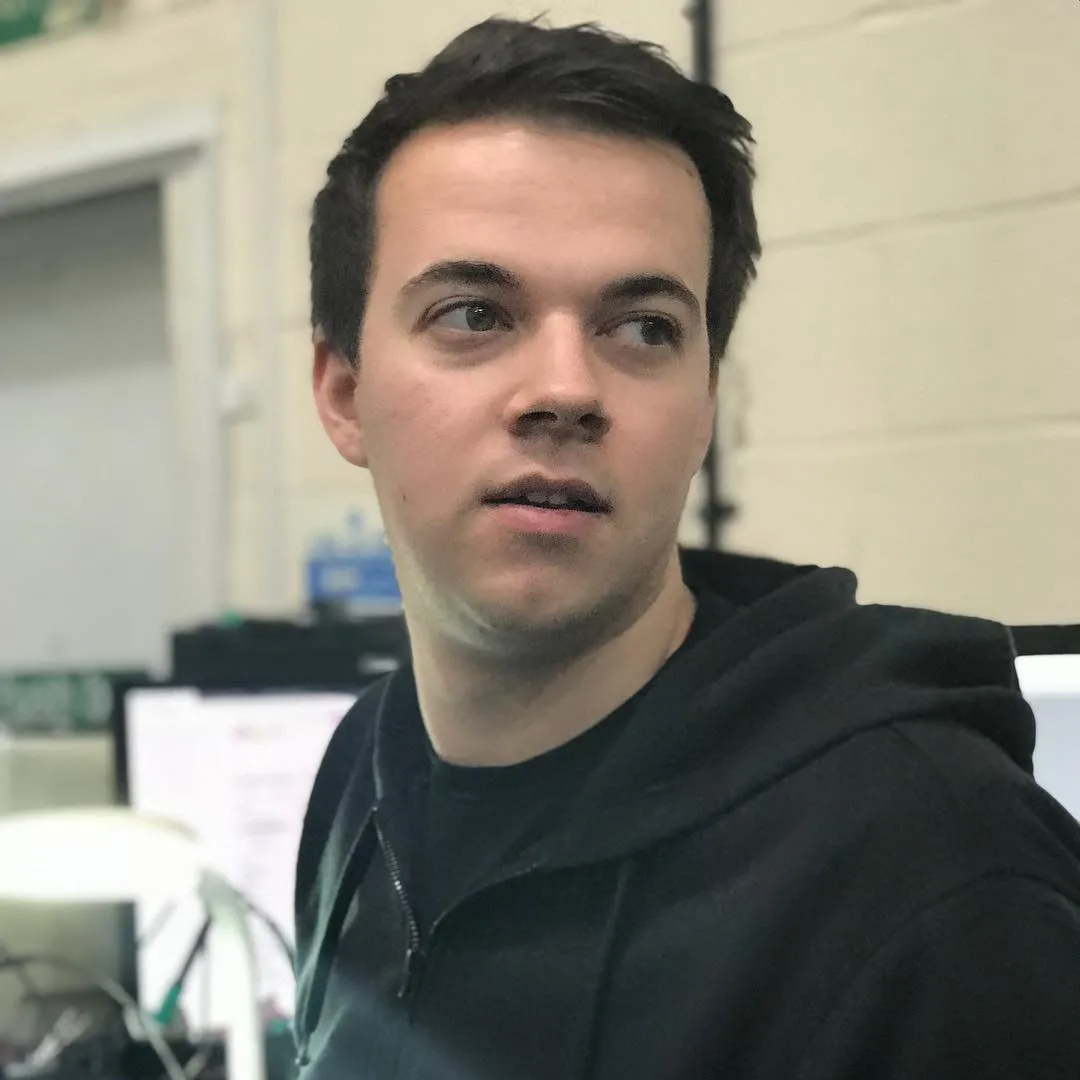 A man in a black hoodie looks to the side of a camera