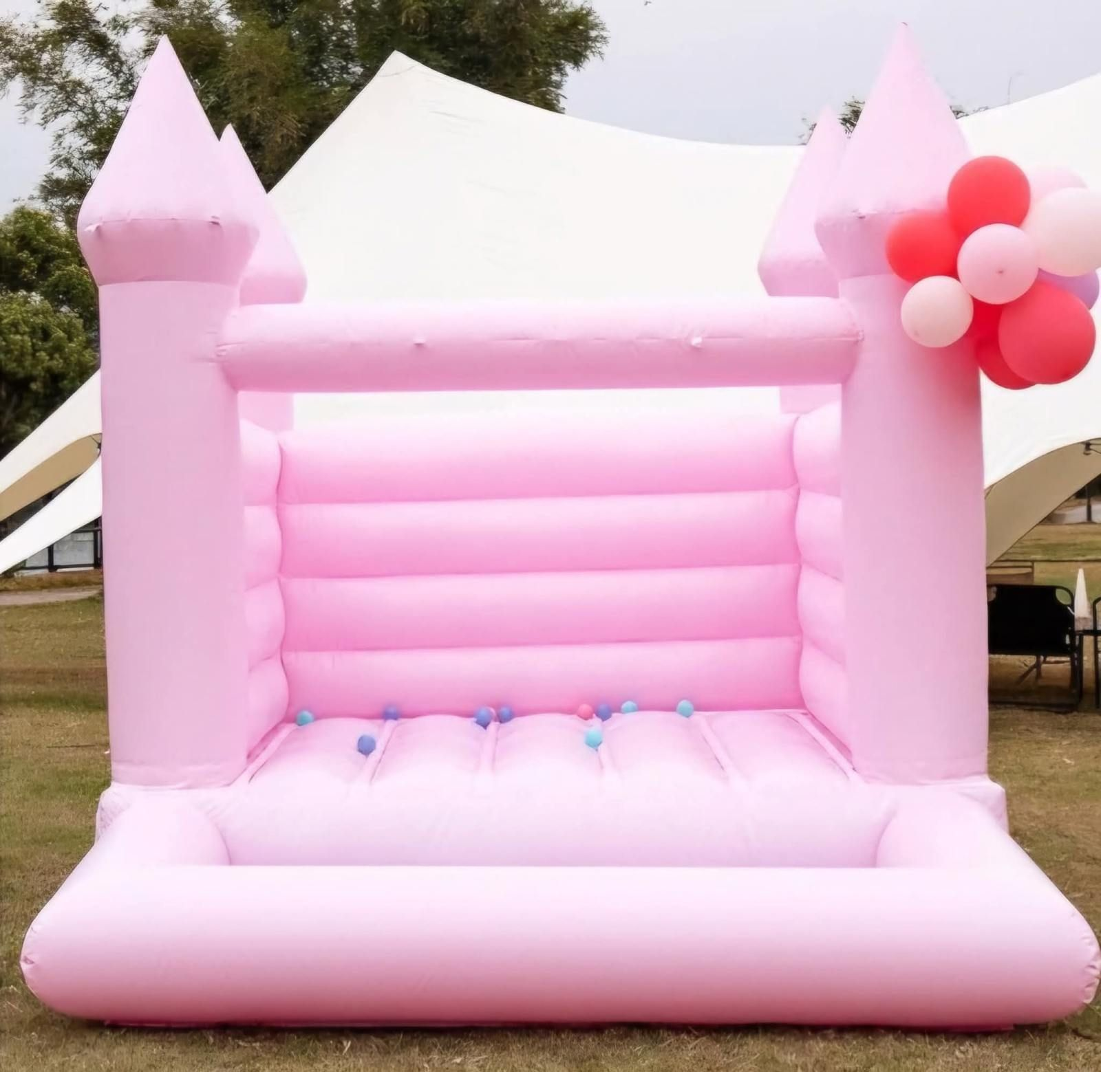Marvel Avengers Bounce House A light pink inflatable bounce house with a castle design, accented by a small cluster of balloons, set on grass.