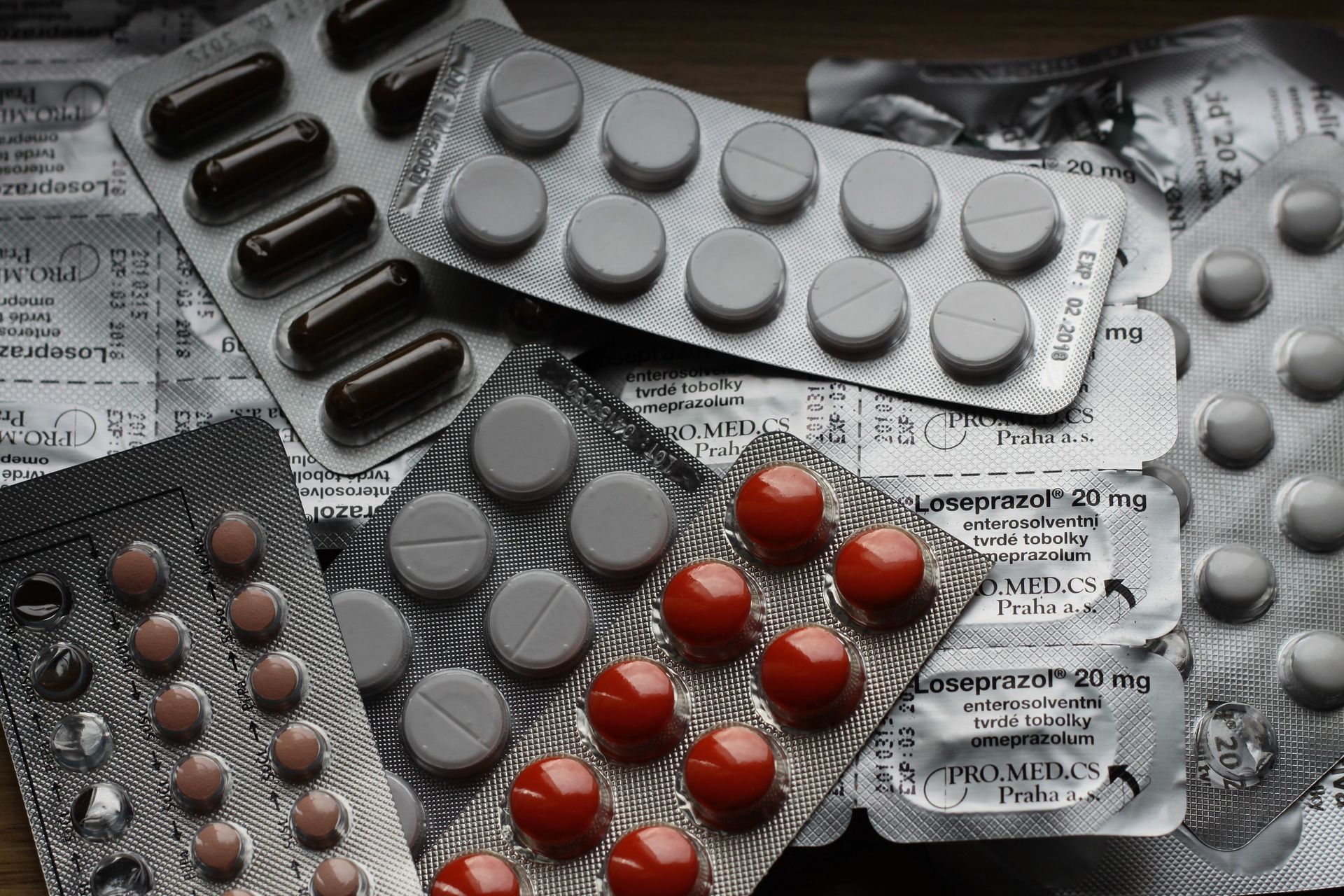Assorted medicine blister packs with pills on a newspaper-covered surface