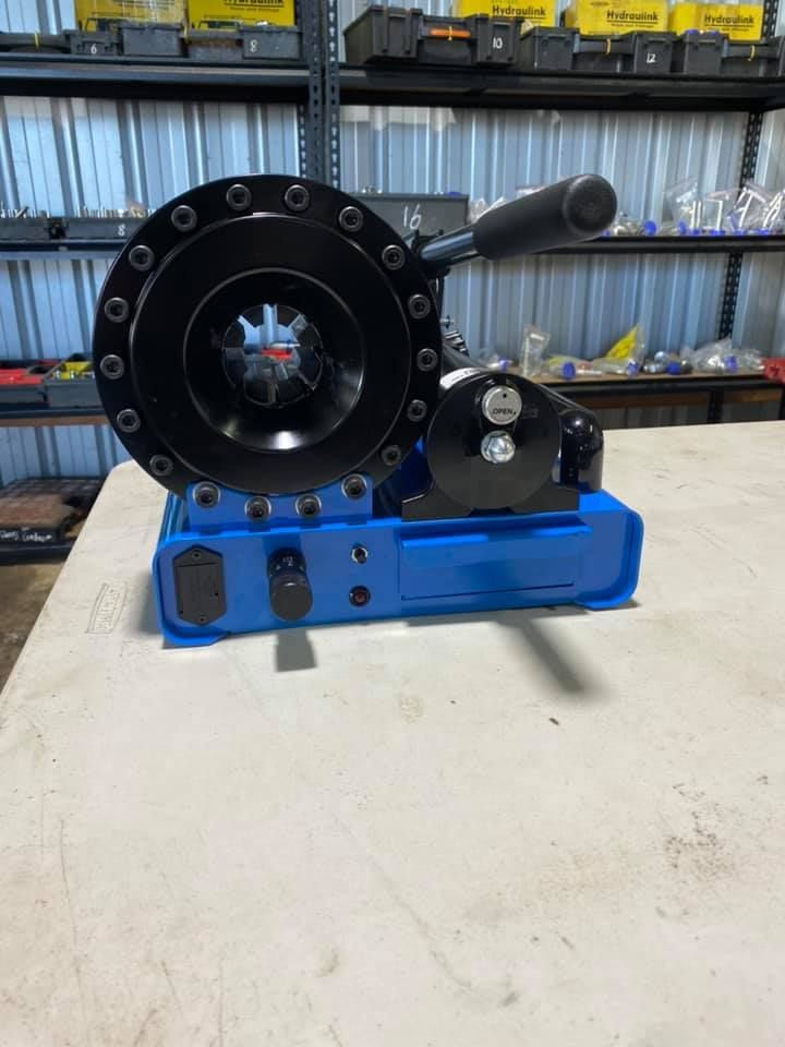 Blue industrial machine part on a workbench in a workshop, with a large black circular housing and side handle.