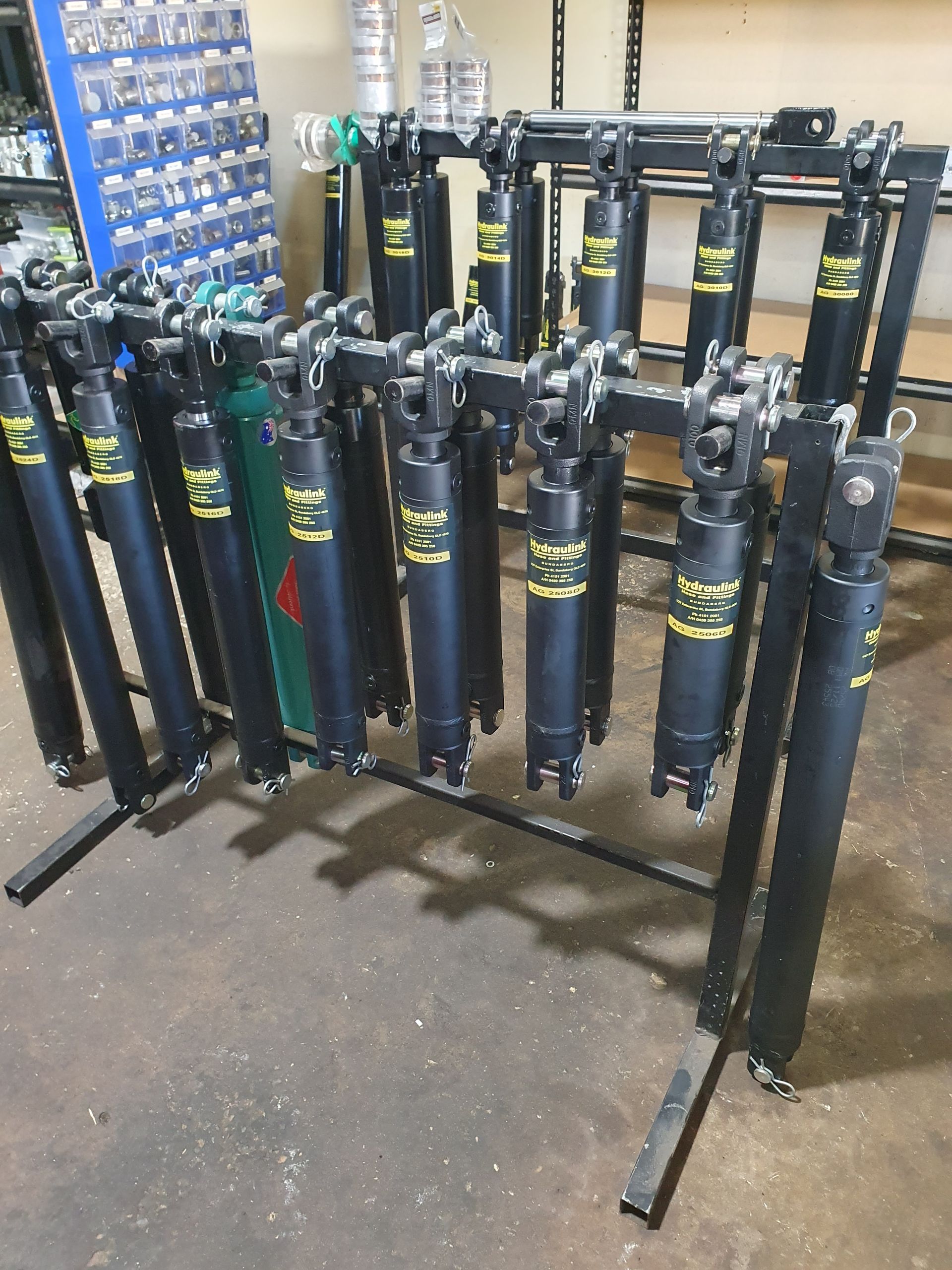 Row of blue electric scooters parked on a metal rack in a shop or warehouse
