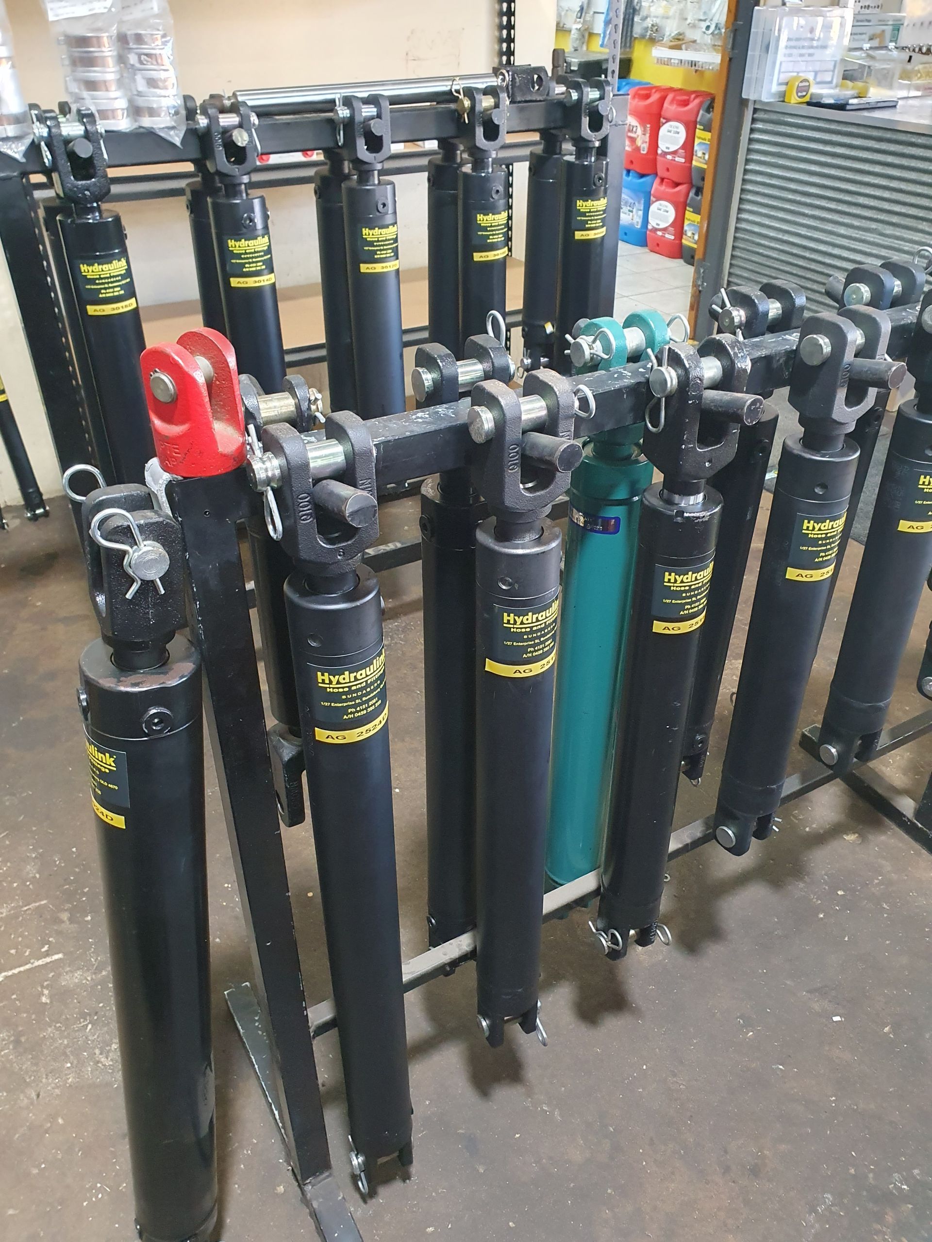 Cluster of black and teal scuba tanks standing upright in a store or workshop rack.