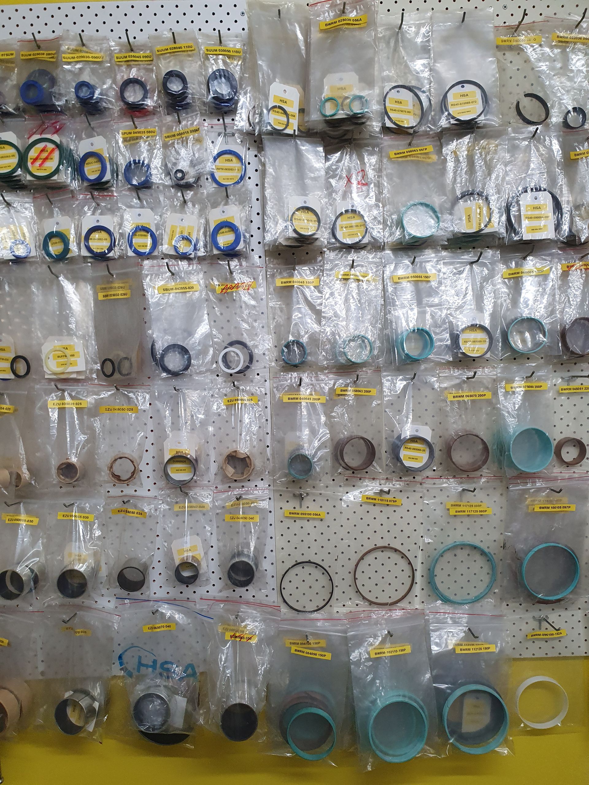 Assorted small round items and accessories displayed on hanging retail hooks against a gray wall.