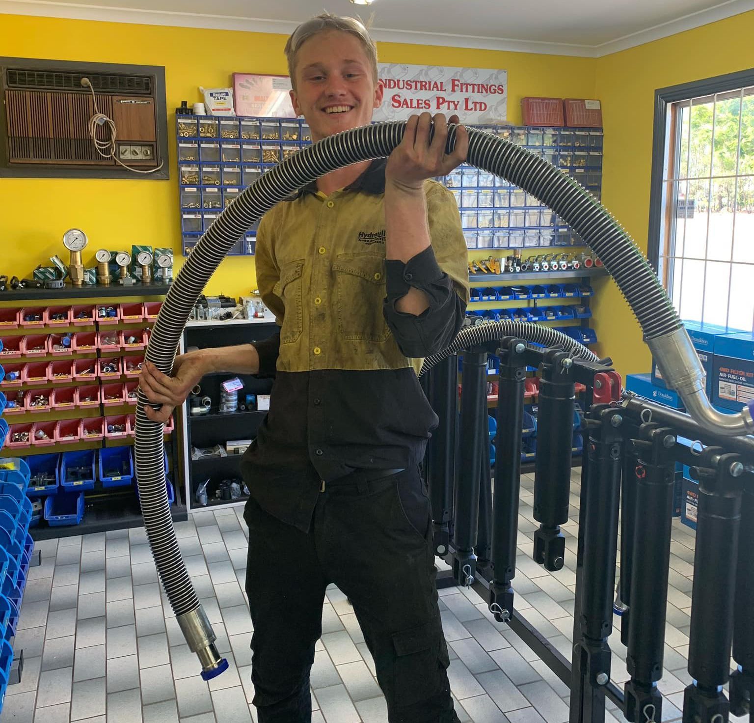 Person holding a large snake inside a brightly lit pet shop, smiling.