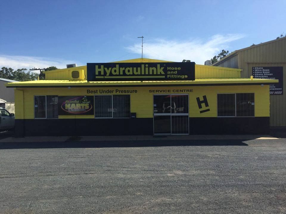 Yellow Hydraulink storefront with black trim and large parking lot in front