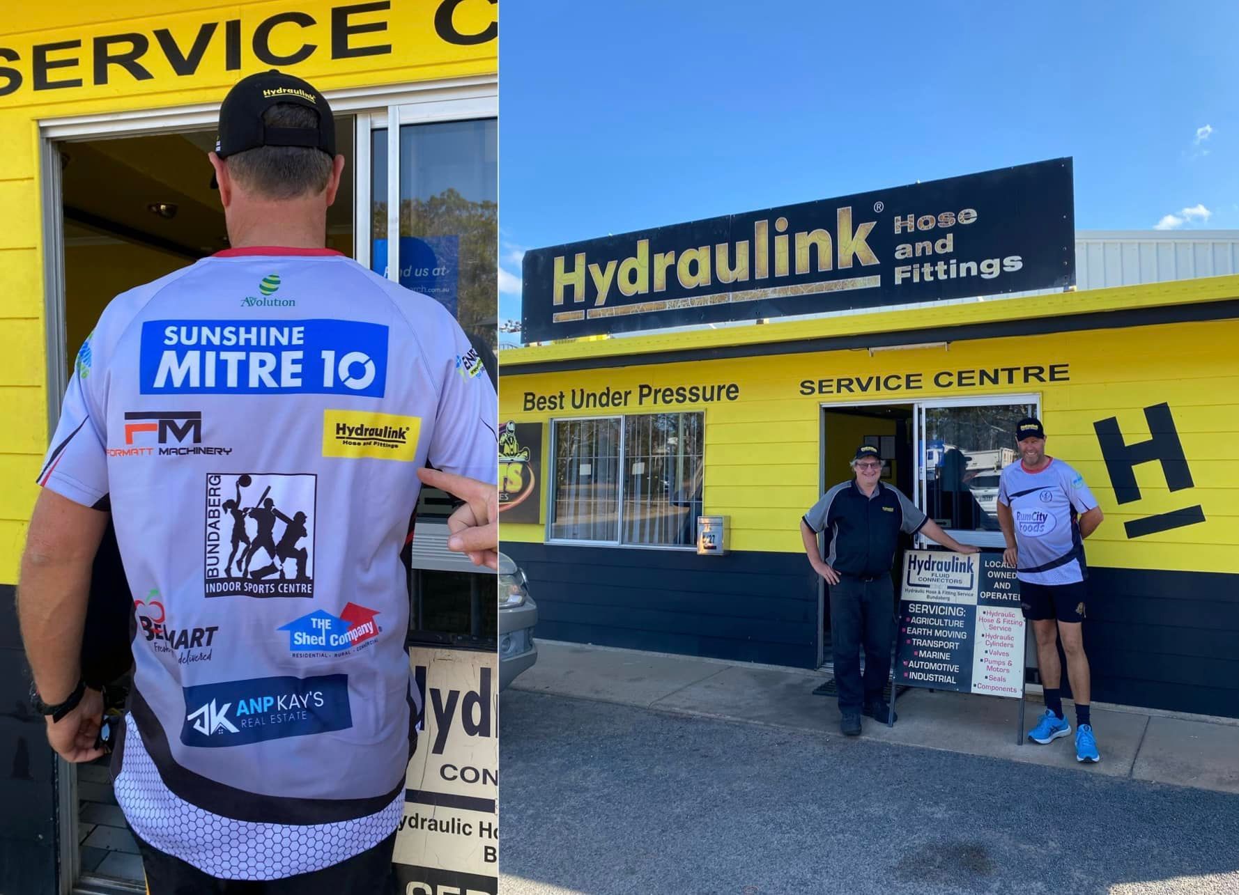 Two people outside Hydraulink service center, one in a sponsor jersey and one beside a signboard.