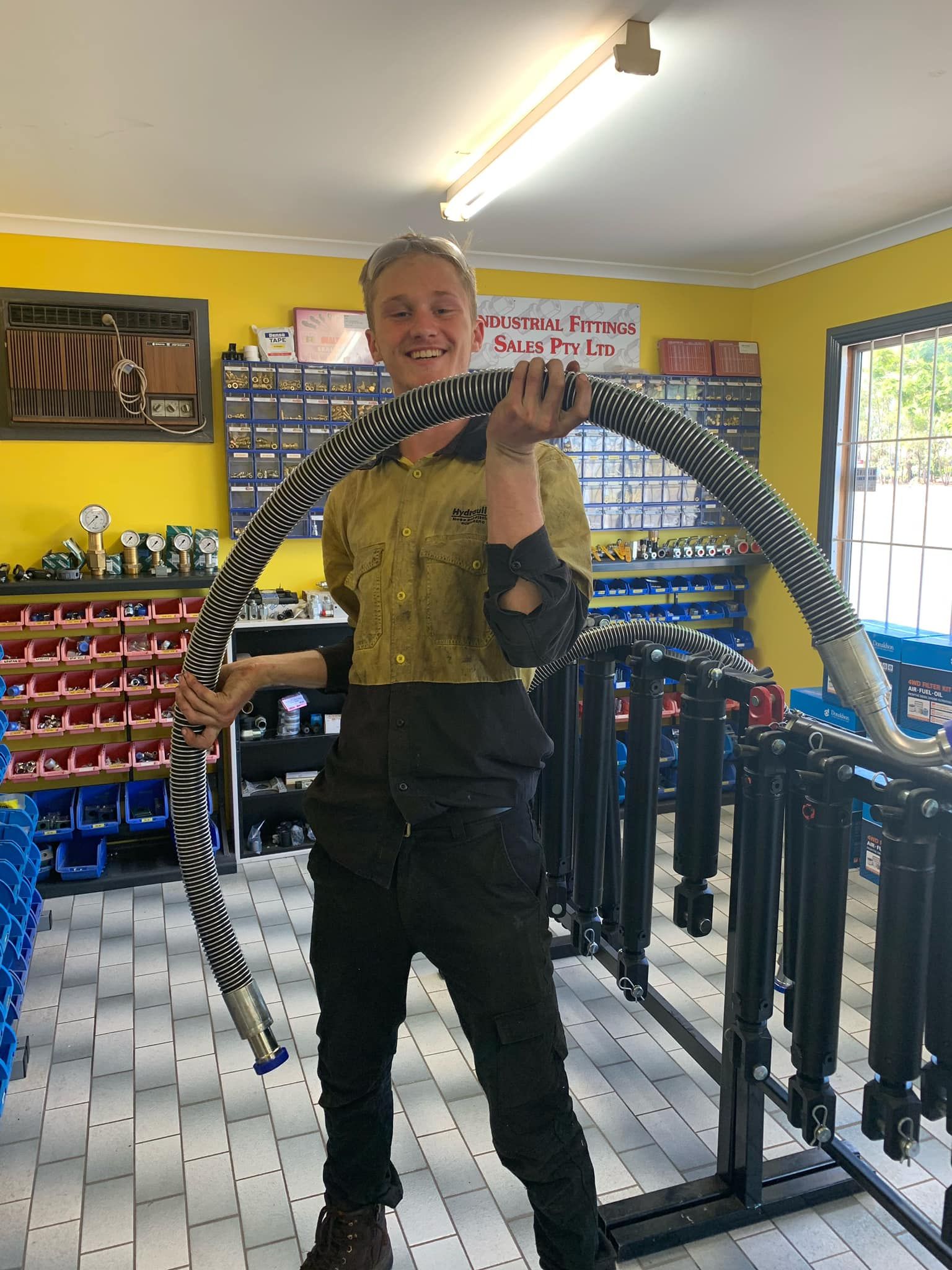 Person holding a large snake in a brightly lit pet shop, with cages and supplies in the background