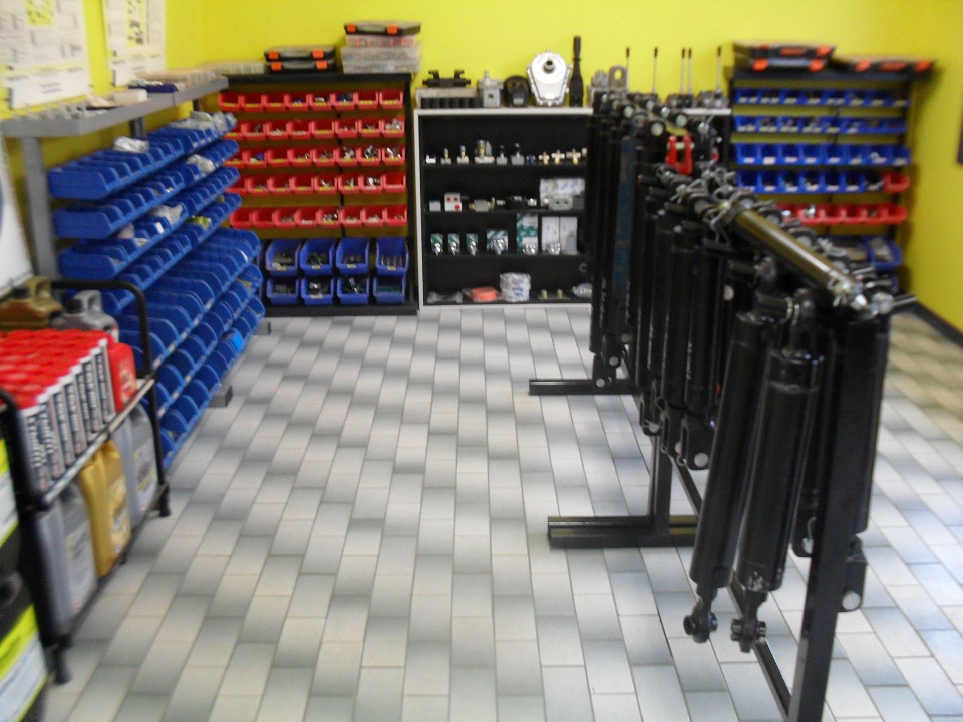 Store aisle with blue, red, and black automotive parts bins along a tiled floor