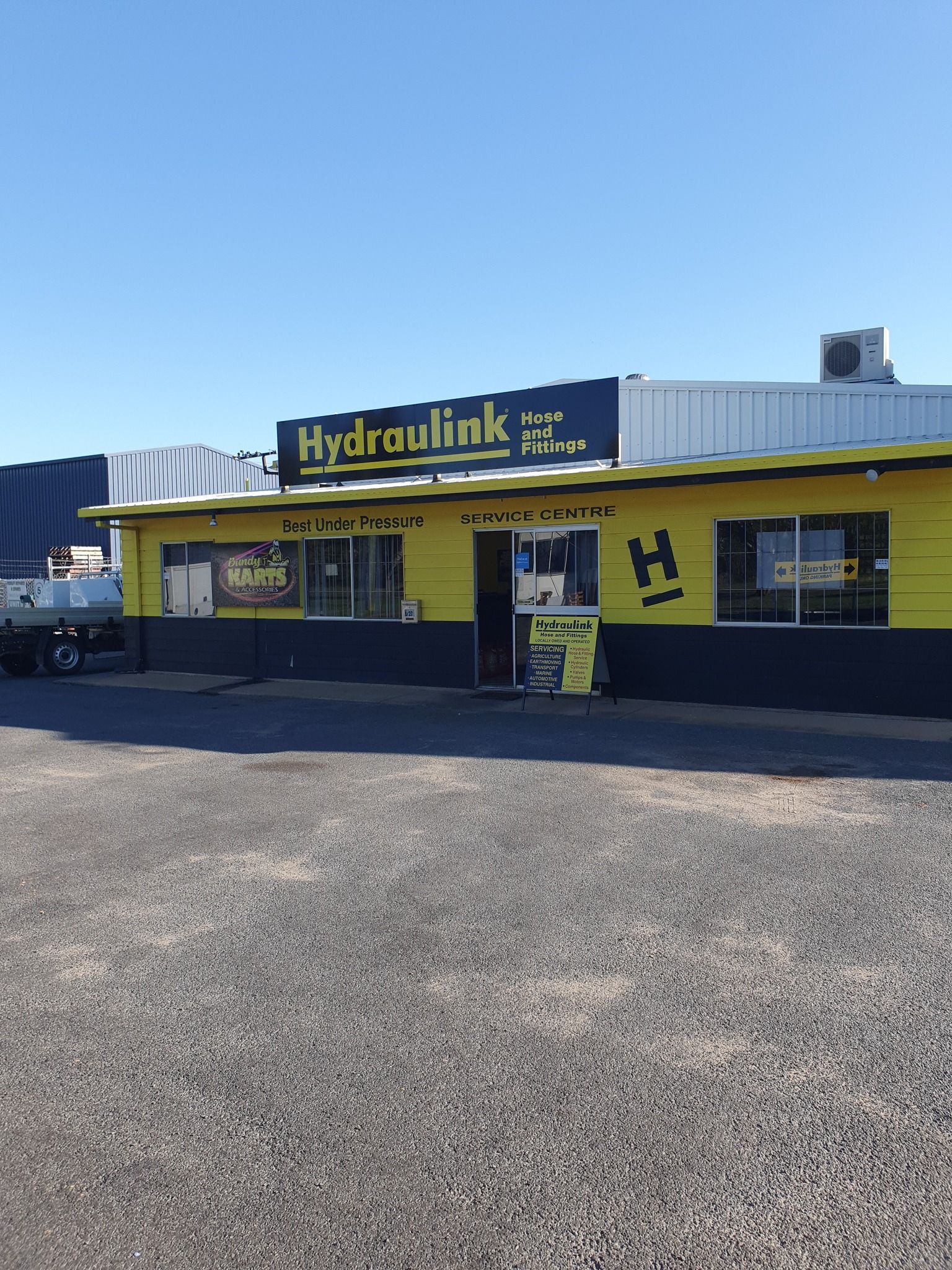 Hydraulink storefront with yellow awning and sign under a clear blue sky