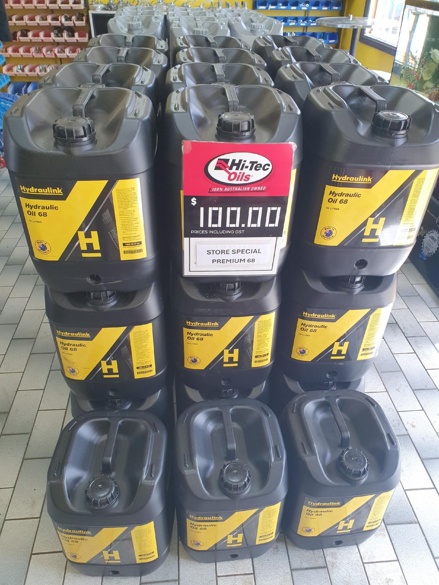 Rows of black plastic jugs with yellow labels stacked around a red-labeled jug in a warehouse aisle