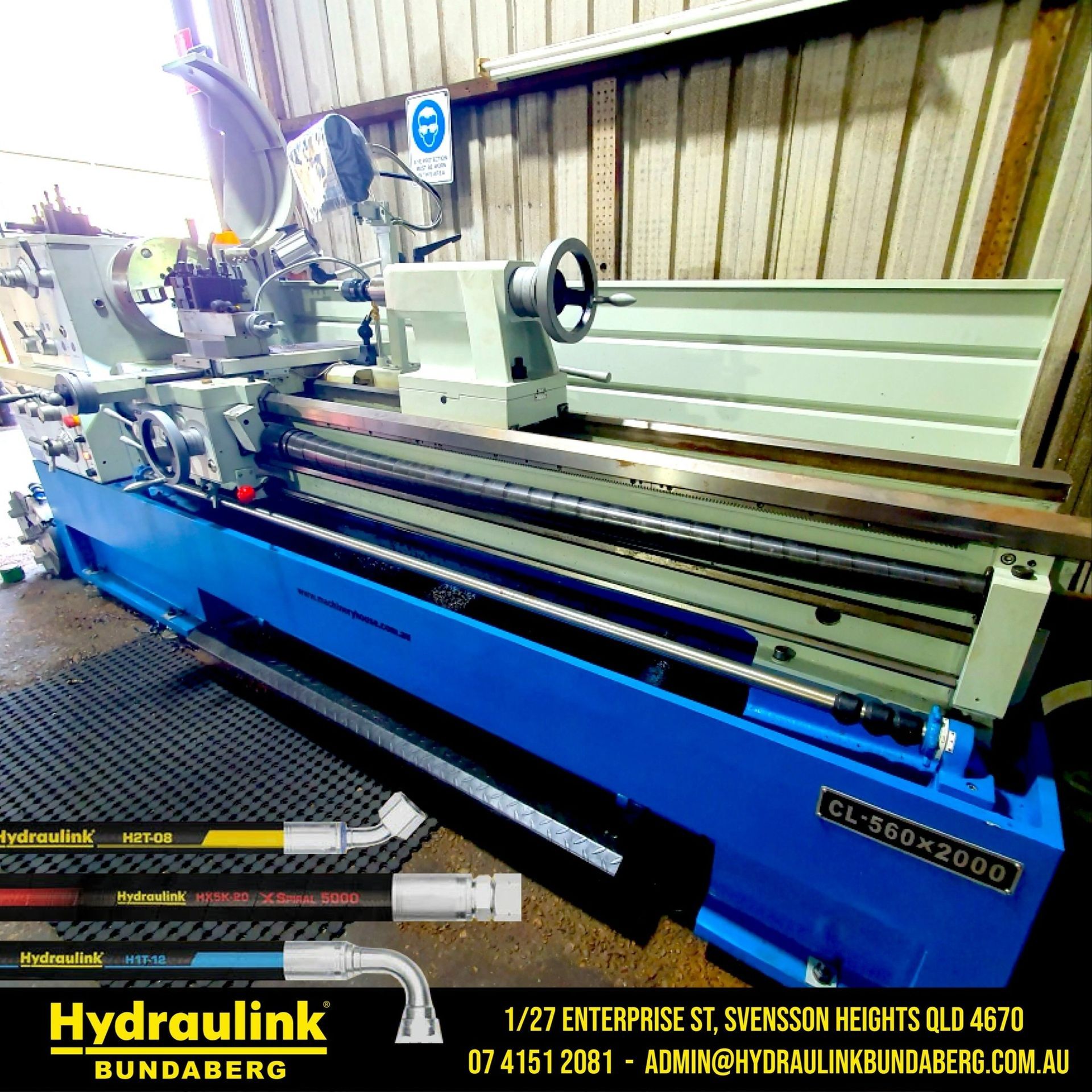 Blue and white metal lathe in a workshop, with controls and long bed visible
