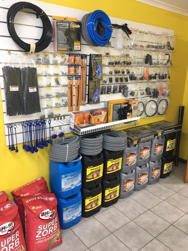 Hardware store wall display with hoses, tools, and stacked bags and buckets on tiled floor