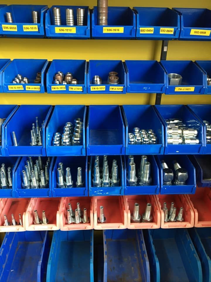 Blue storage bins filled with assorted bolts and screws on a workshop shelf