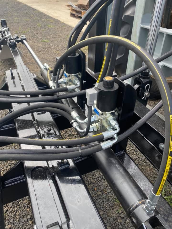 Hydraulic hoses and metal fittings on black industrial equipment outdoors