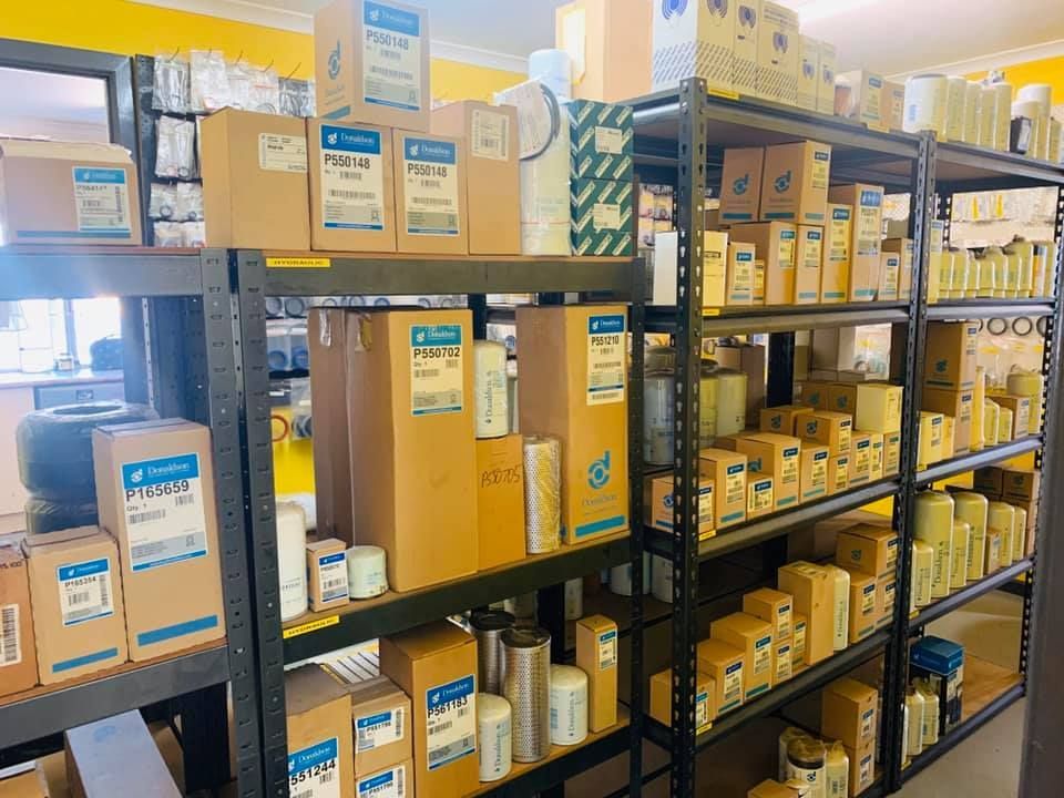 Shelves stocked with boxed and bottled supplies in a bright warehouse aisle