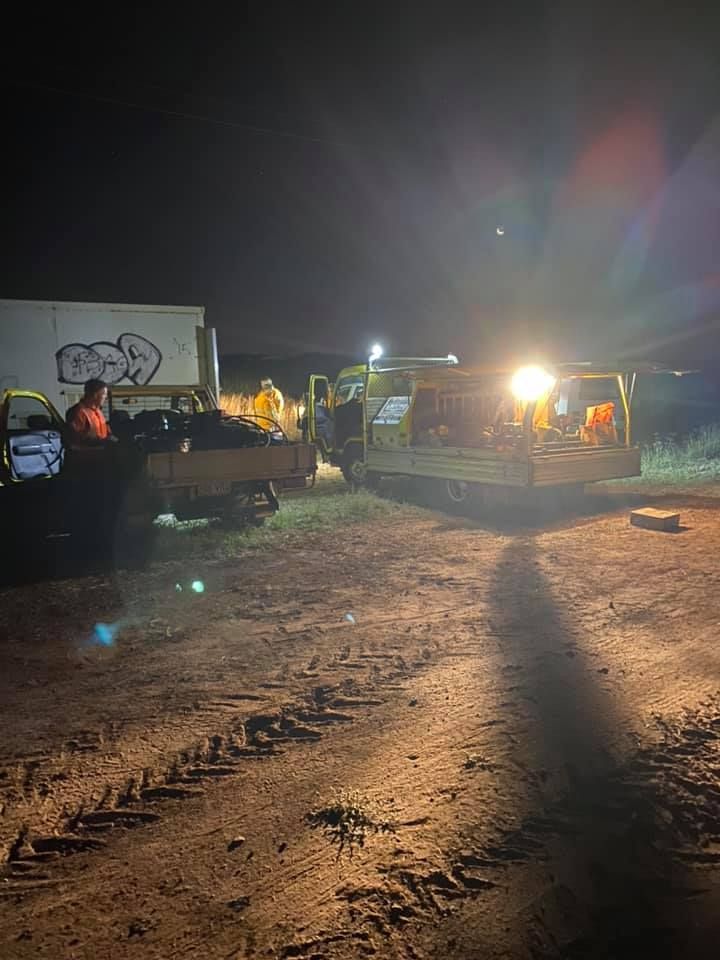 Nighttime construction site with excavators and bright work lights on a dirt road
