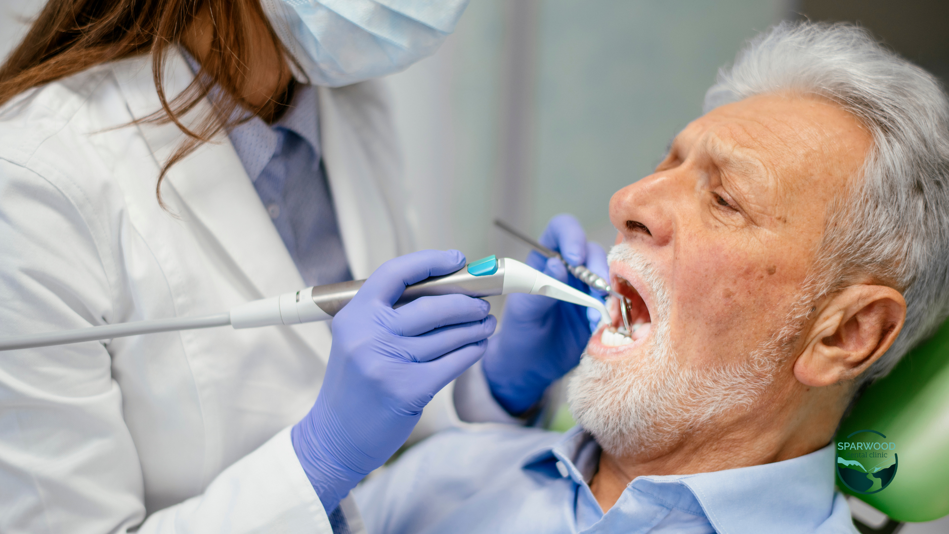 An elderly man is getting his teeth examined by a dentist.
