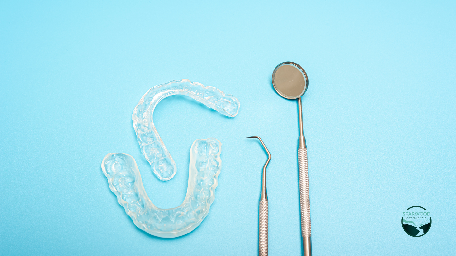 A dental mirror , dental instruments , and teeth whitening tray on a blue background.