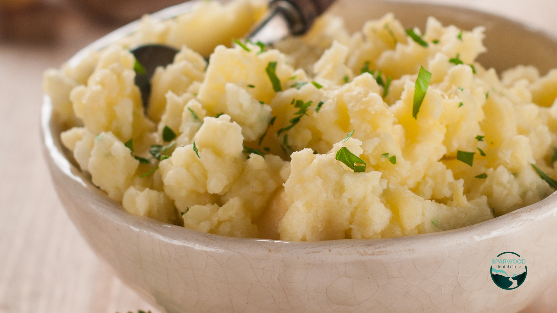 A bowl of mashed potatoes with a spoon in it.