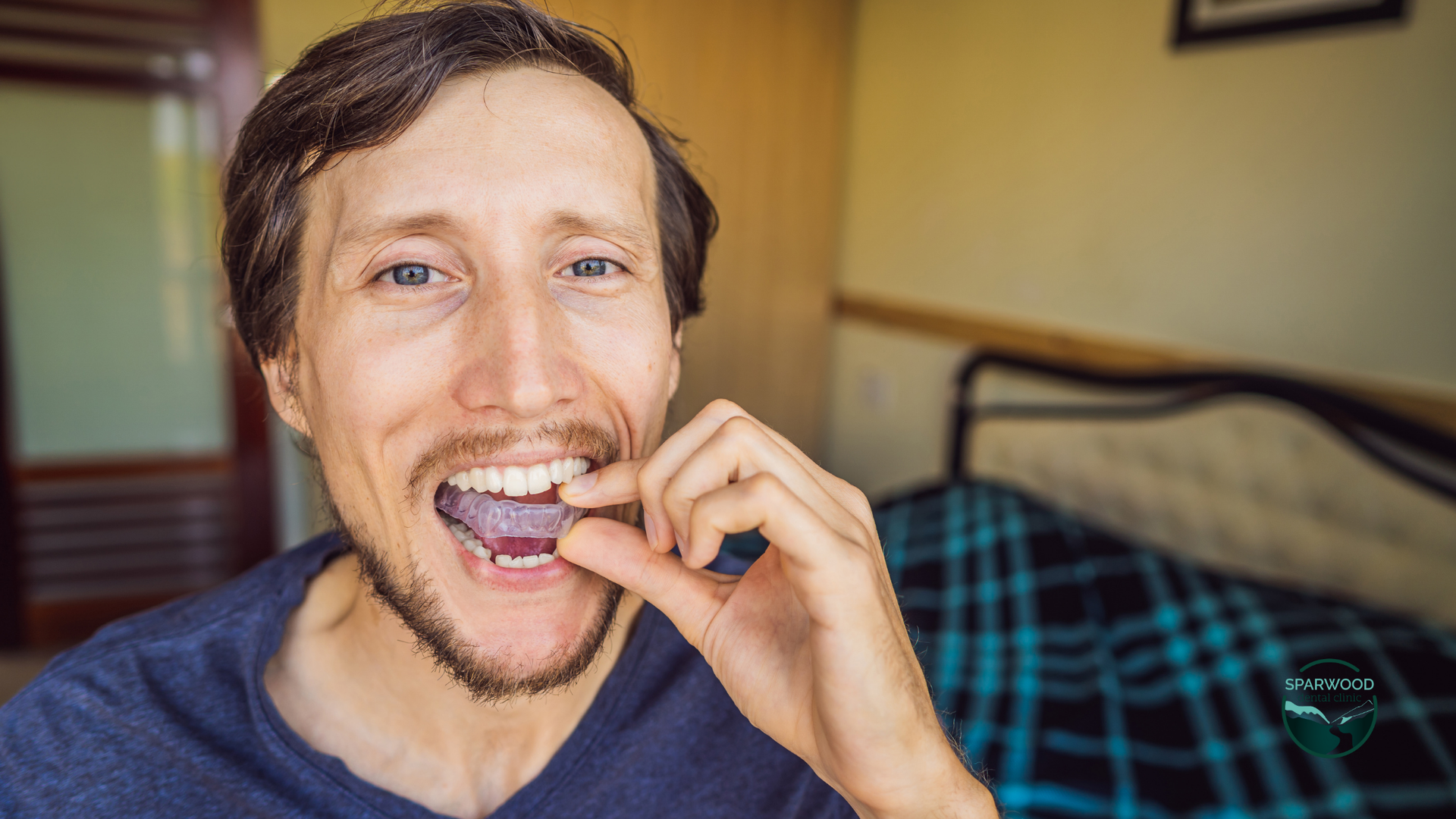 A man with a beard is biting a piece of gum in his mouth.
