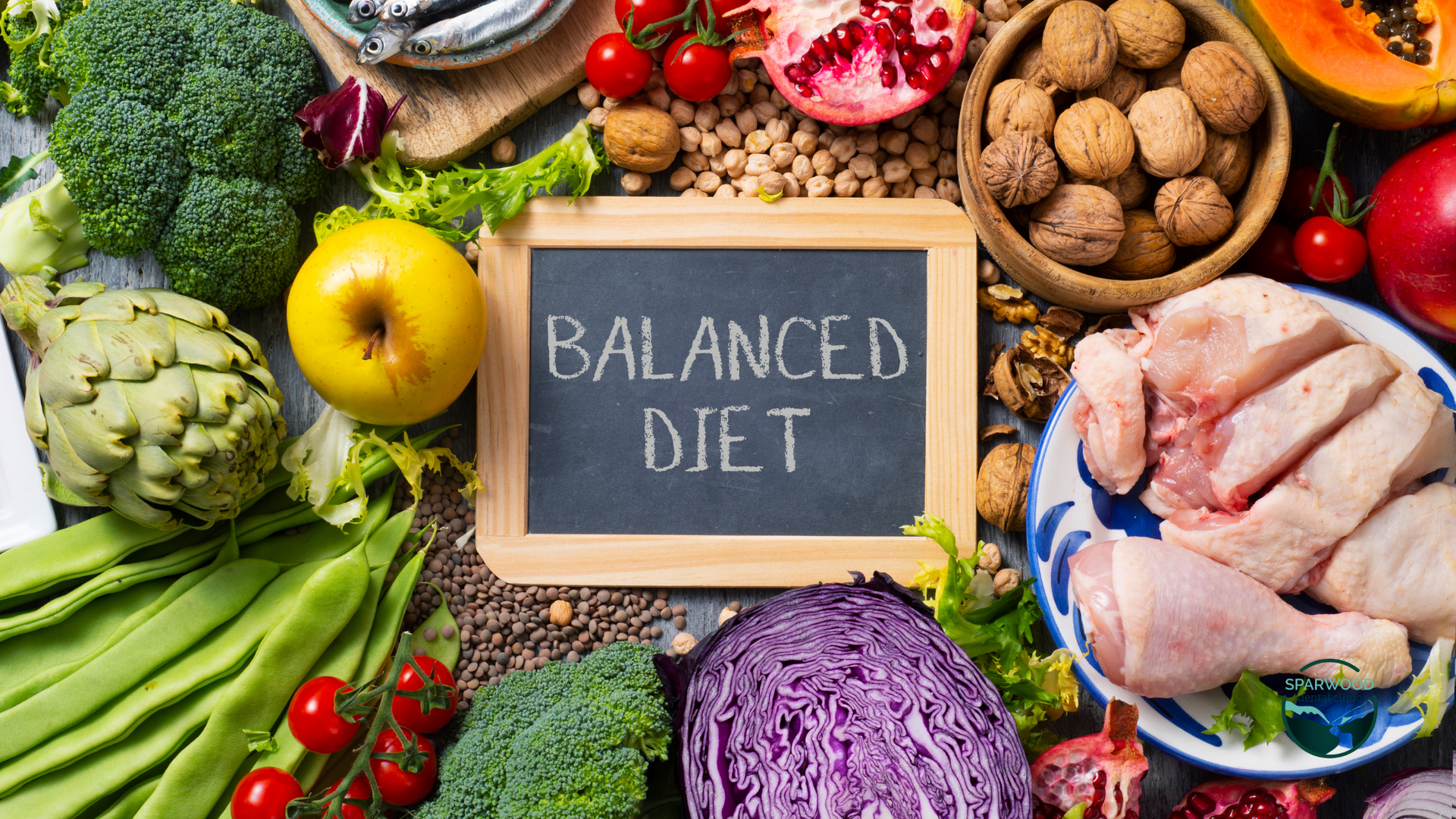 A balanced diet is written on a blackboard surrounded by fruits and vegetables.