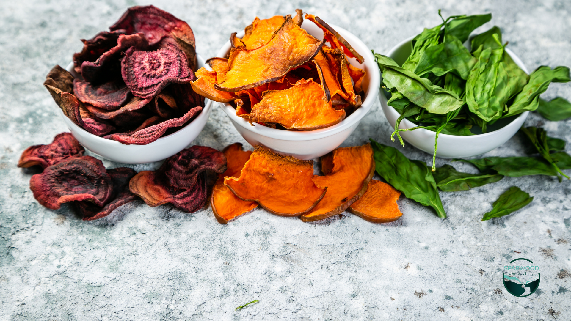 Three bowls of different types of chips and spinach on a table.