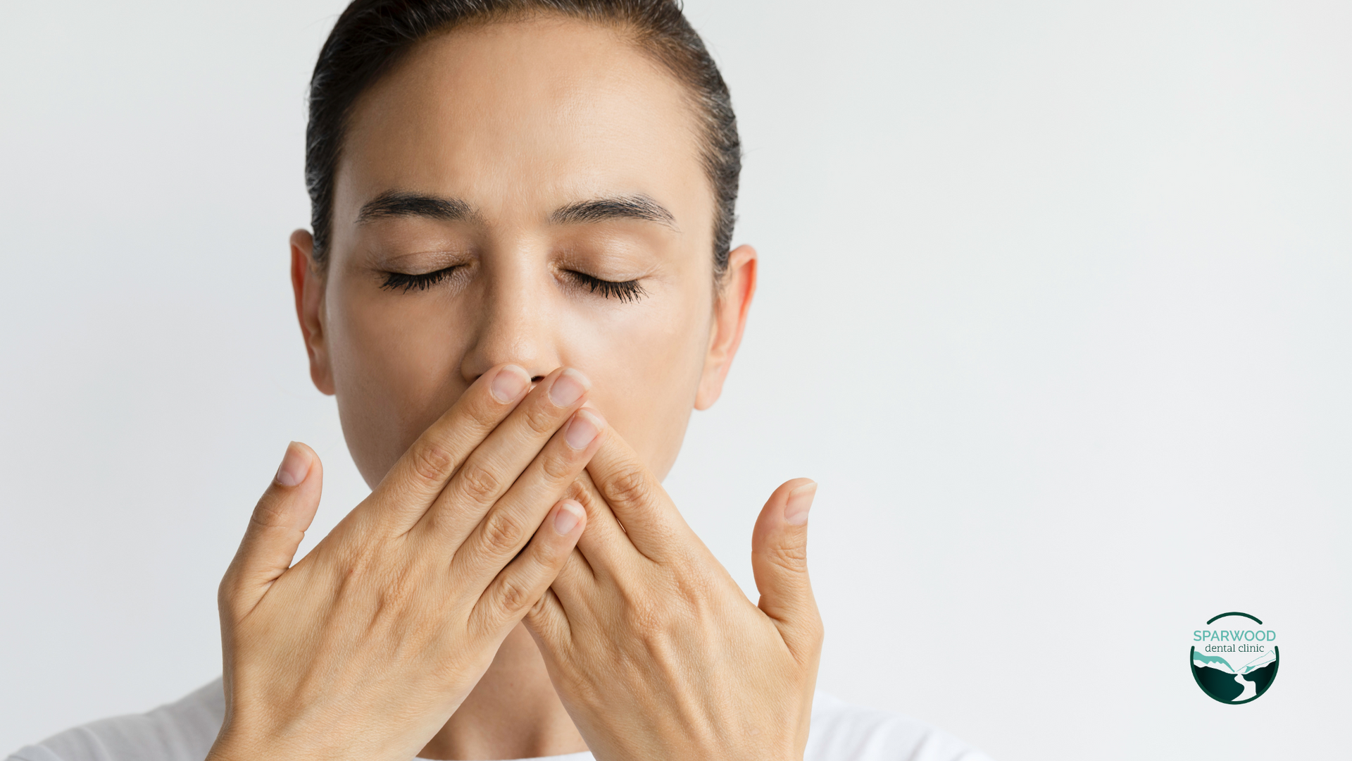 A woman is covering her mouth with her hands.