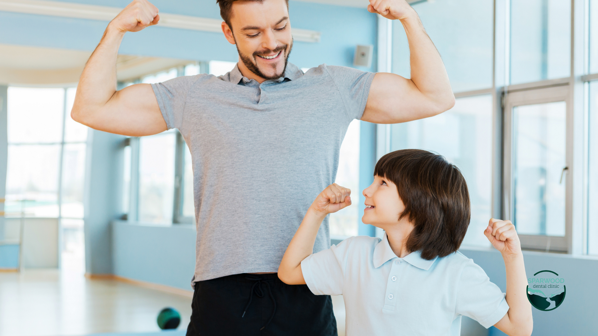 A man and a boy are flexing their muscles in a gym.