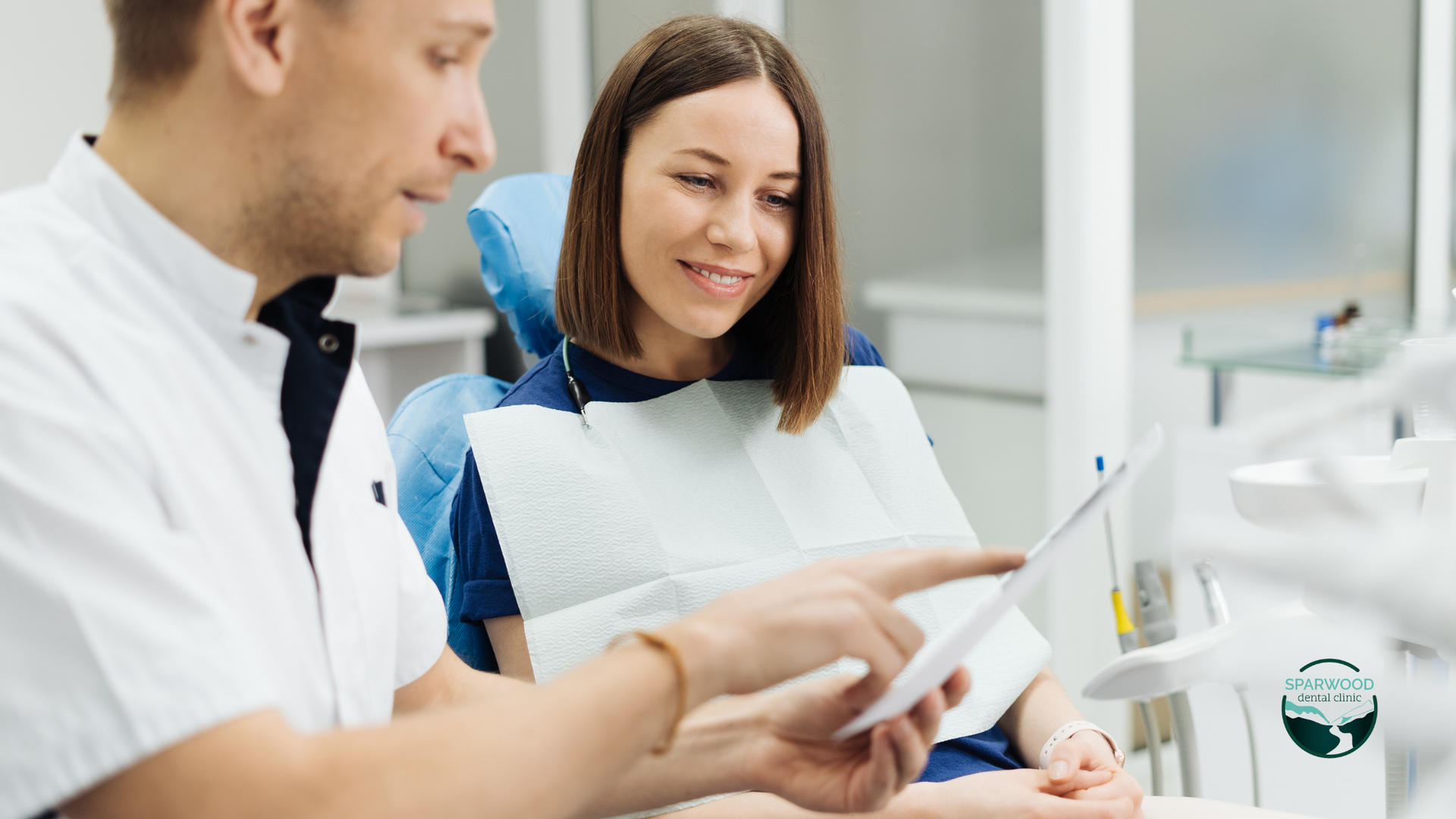A dentist is talking to a patient in a dental chair.