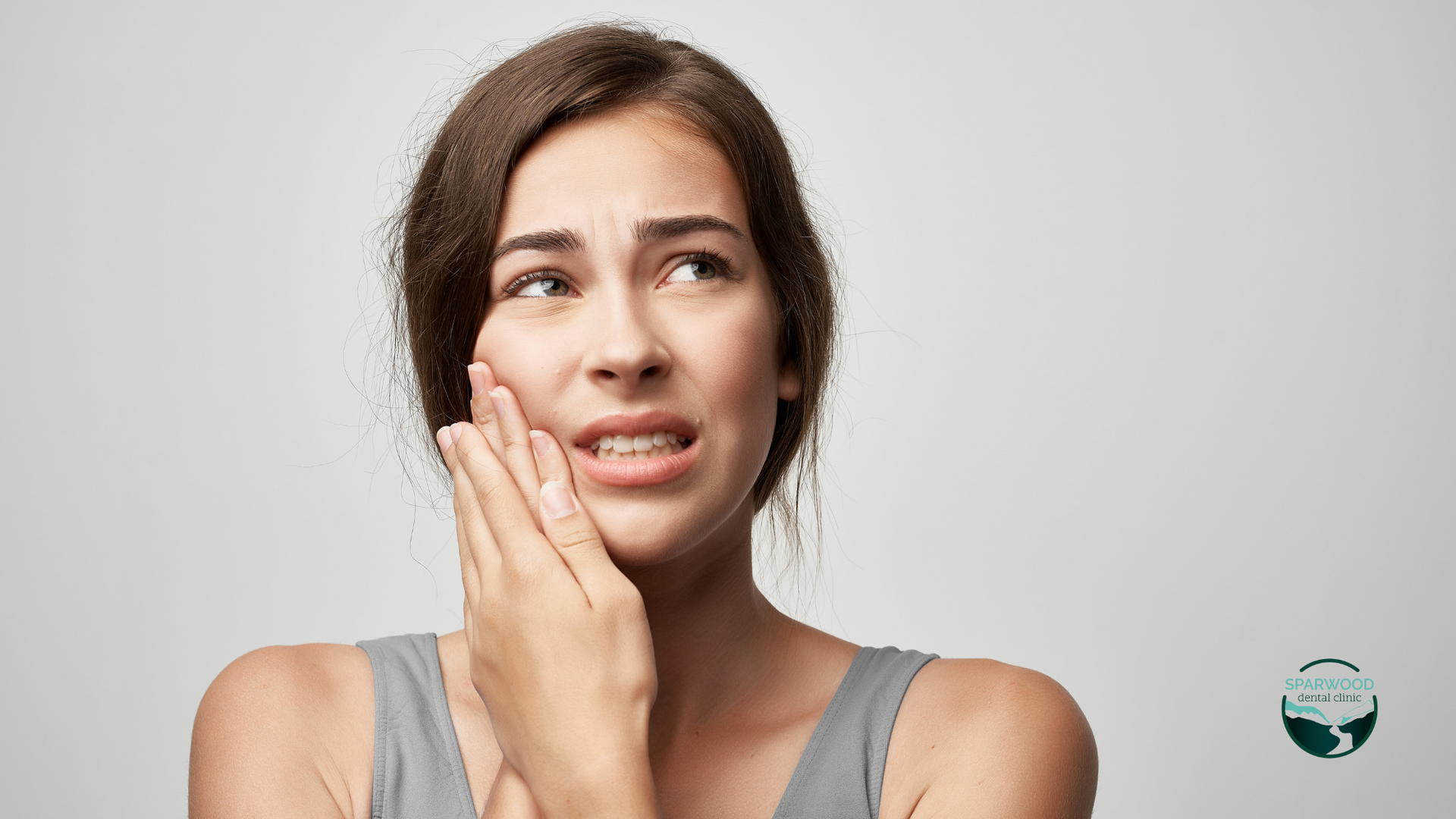 A woman is holding her face in pain because of a toothache.