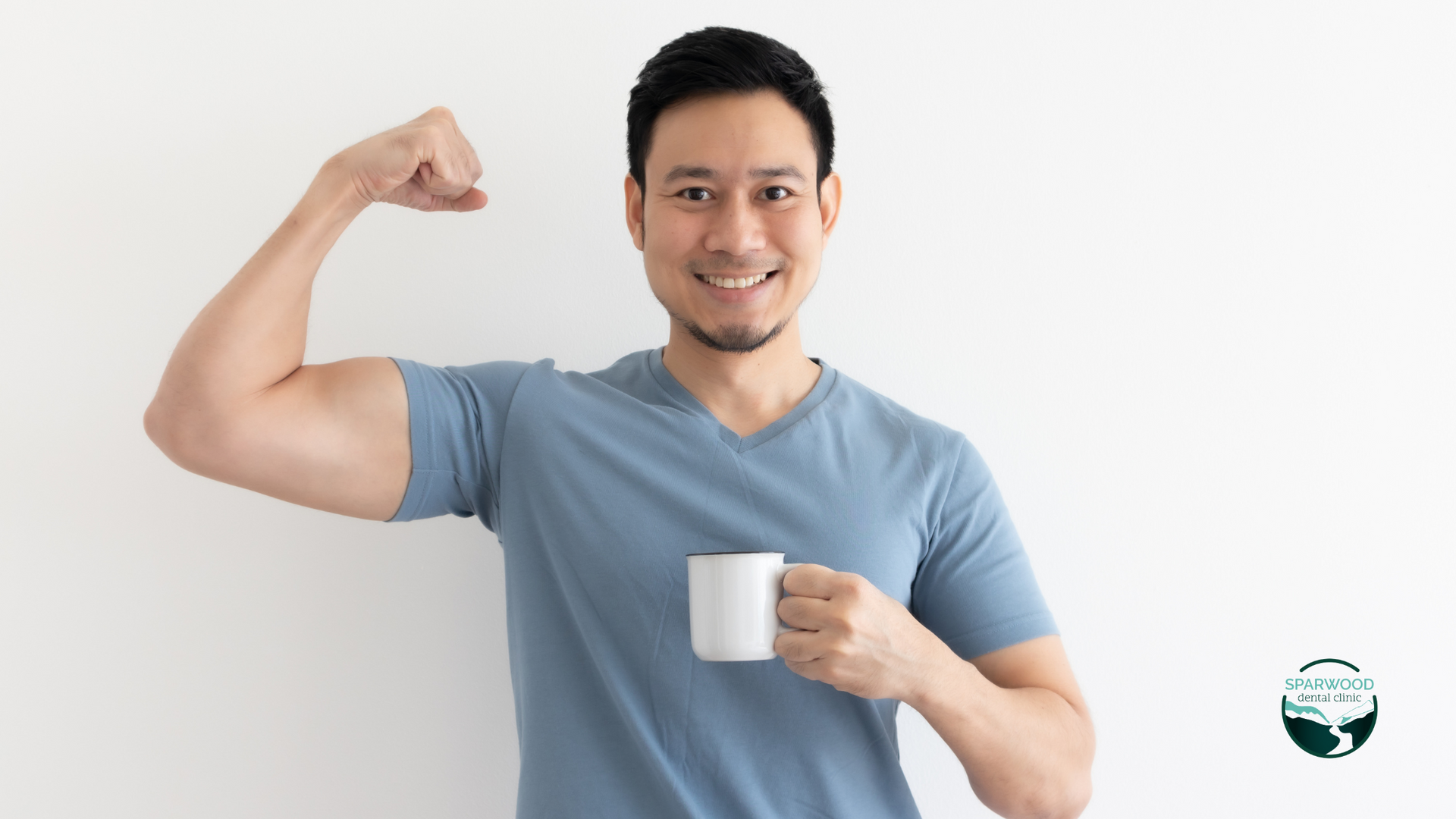 A man is flexing his muscles while holding a cup of coffee.