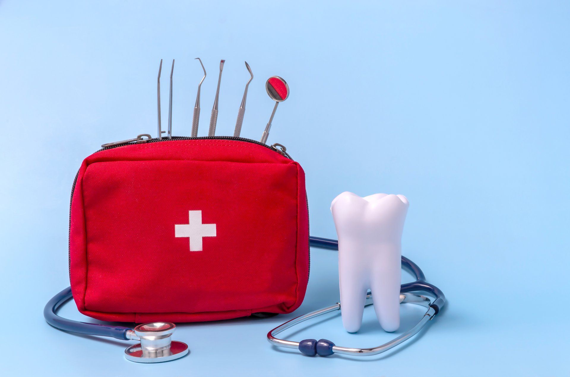 A red first aid kit with a tooth and a stethoscope on a blue background.