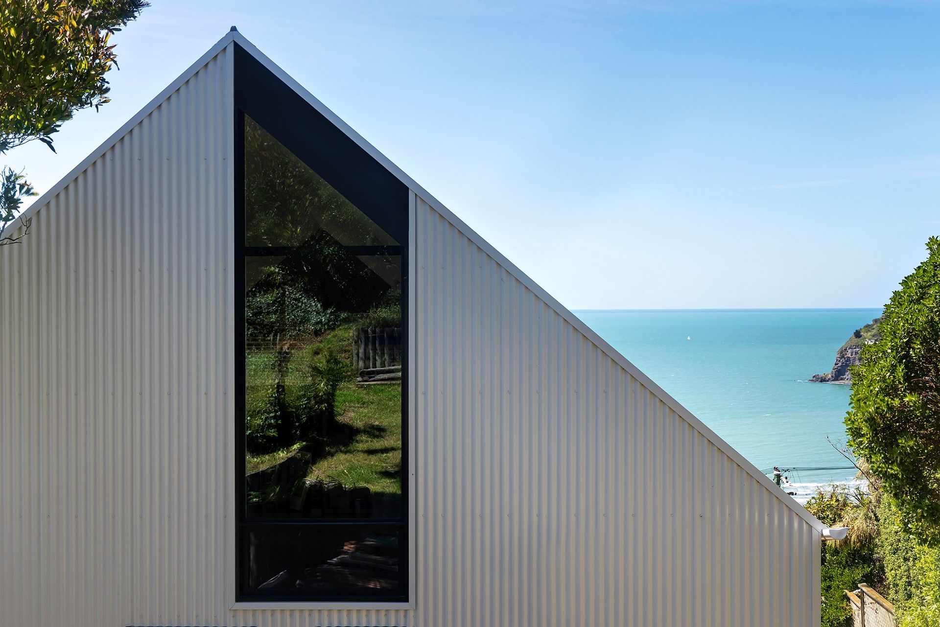 Modern white building with a triangular roof, overlooking the ocean through a large window