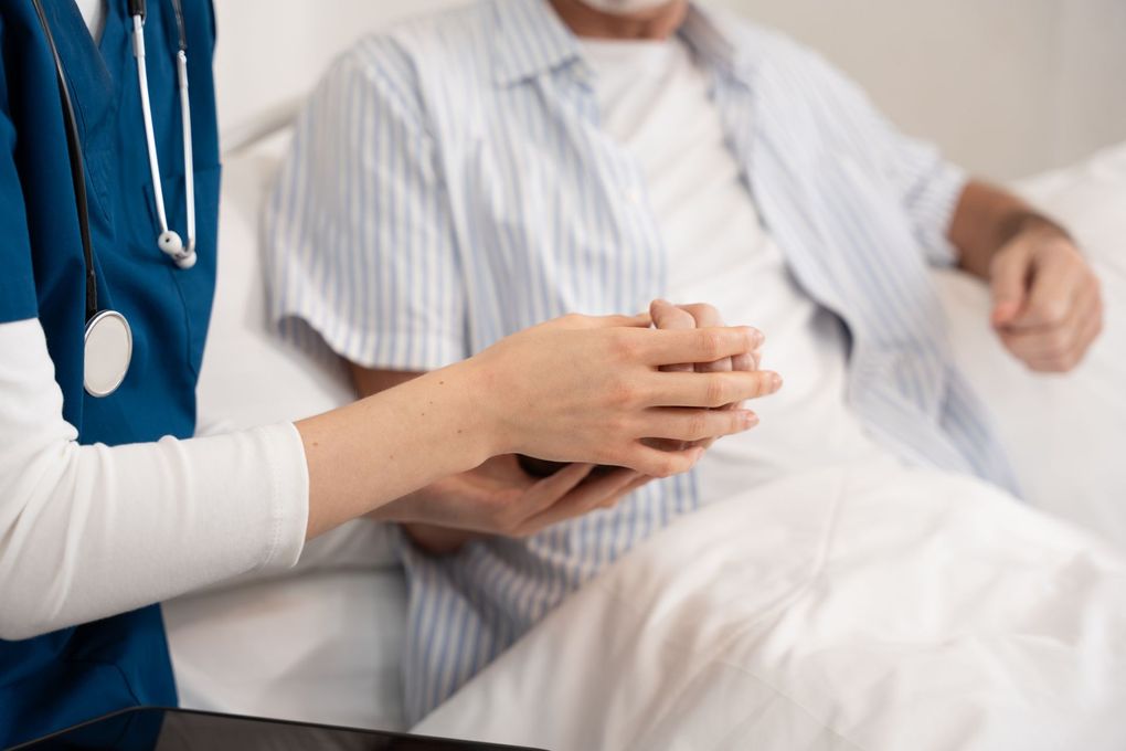 Doctor holding a patient’s hands in a hospital room