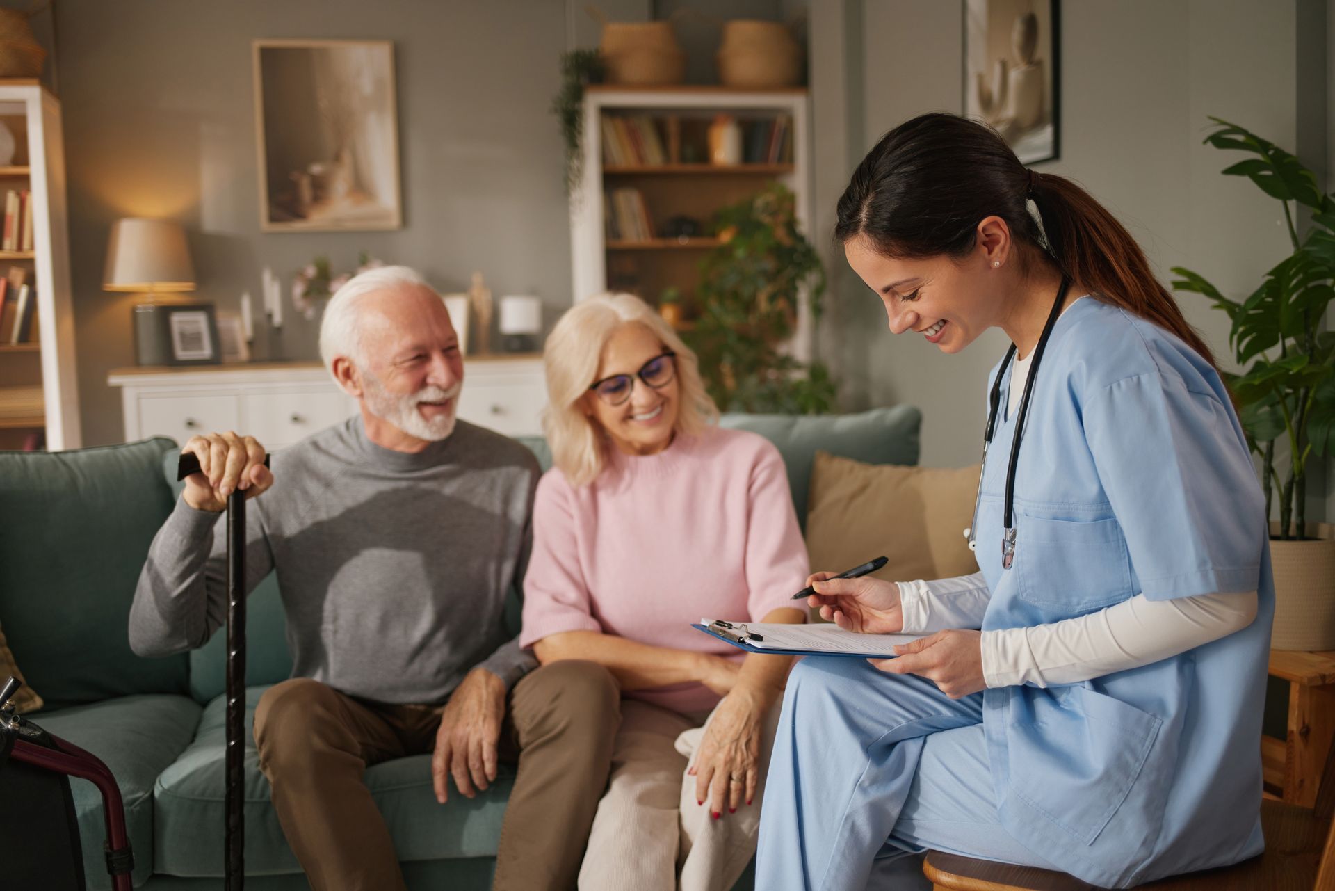 Caregiver taking notes while talking with an older couple in a cozy living room