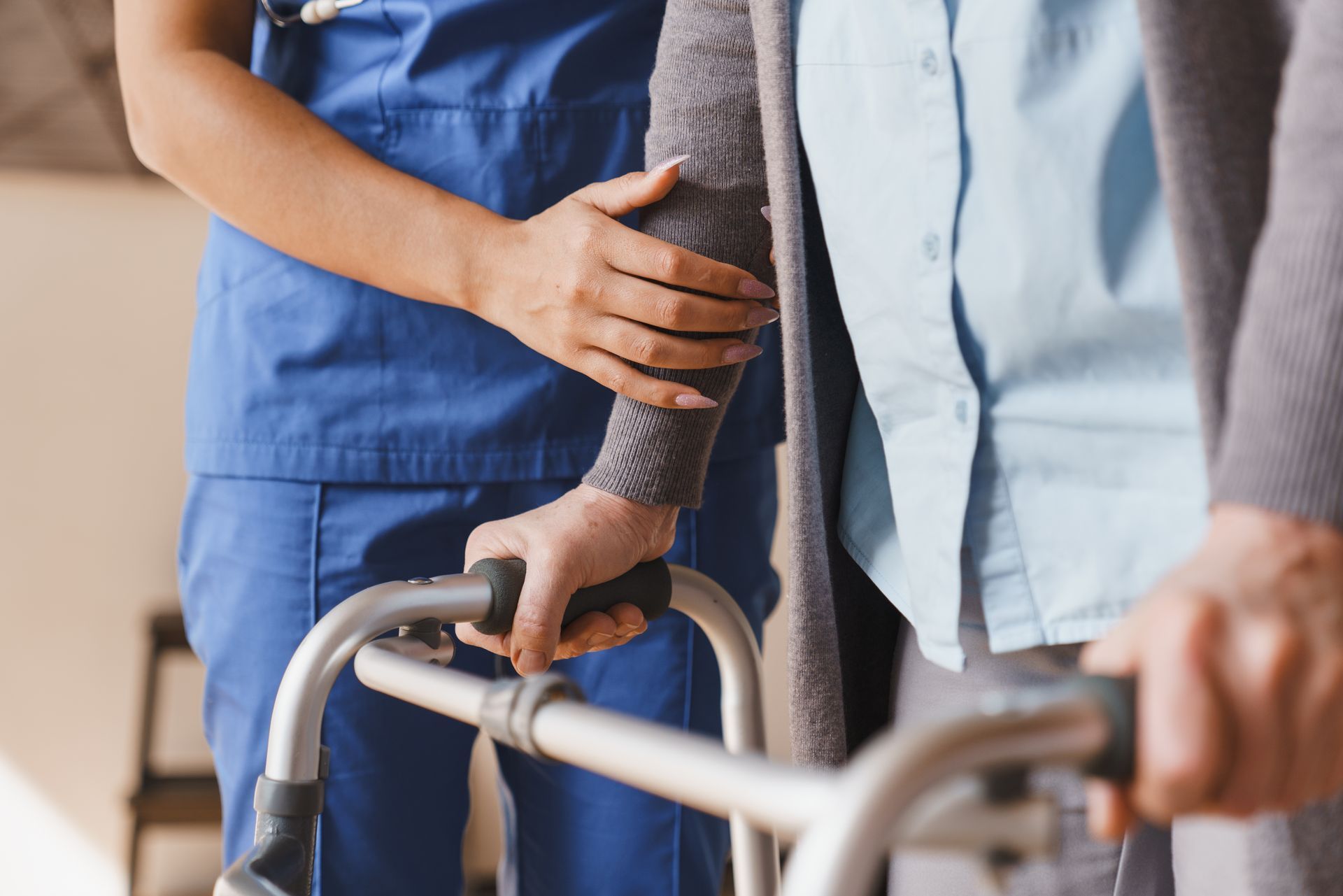 Caregiver assisting an older person with a walker, hands on the handle in a close-up indoor scene Caregiver assisting an older person with a walker, hands on the handle in a close-up indoor scene