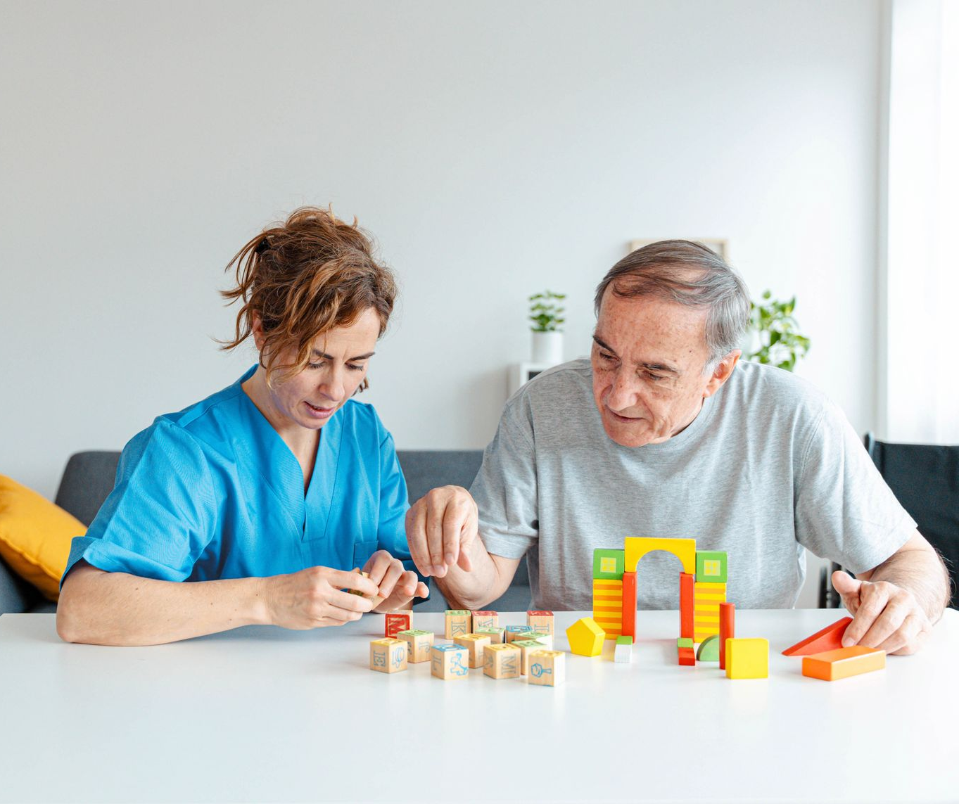 Two people play a board game at a table in a bright living room with toy blocks nearby Two people play a board game at a table in a bright living room with toy blocks nearby