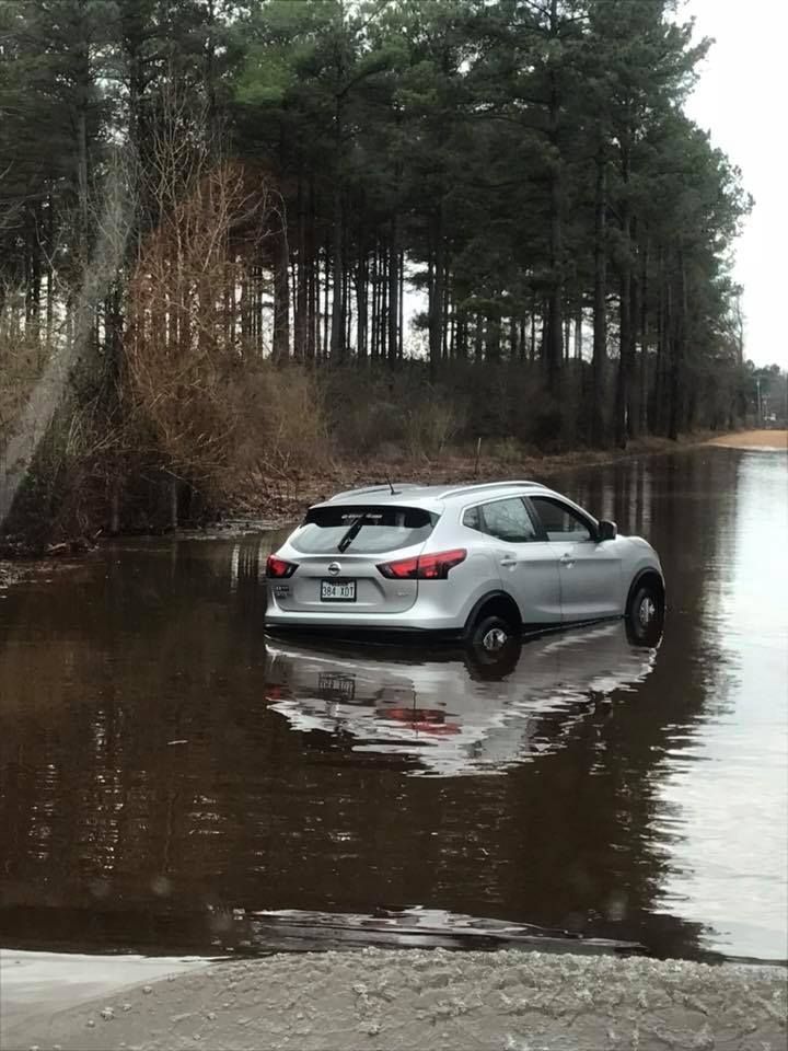 Silver SUV driving through a flooded forest road