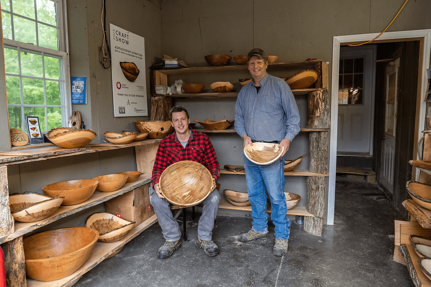 Two men in a wood working studio holding hand carved wooden bowls