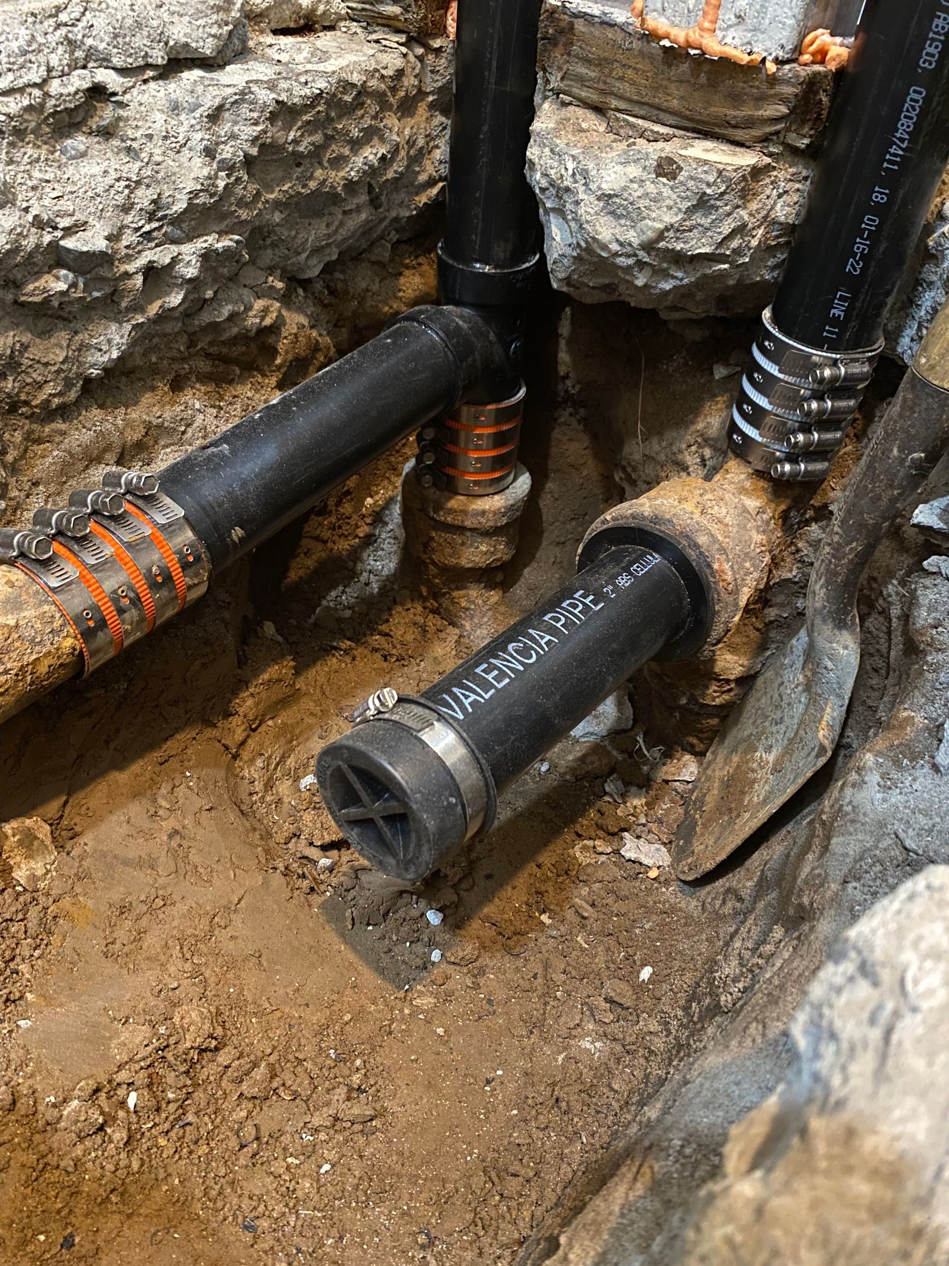 A bunch of pipes are laying in the dirt.